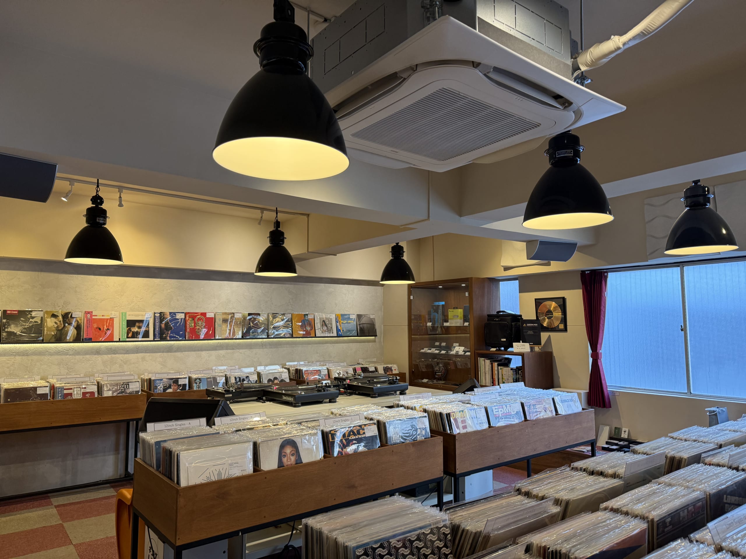 温かな光が照らす、木製ラックに整然とレコードが並ぶ銀座レコード蔵前の店内。