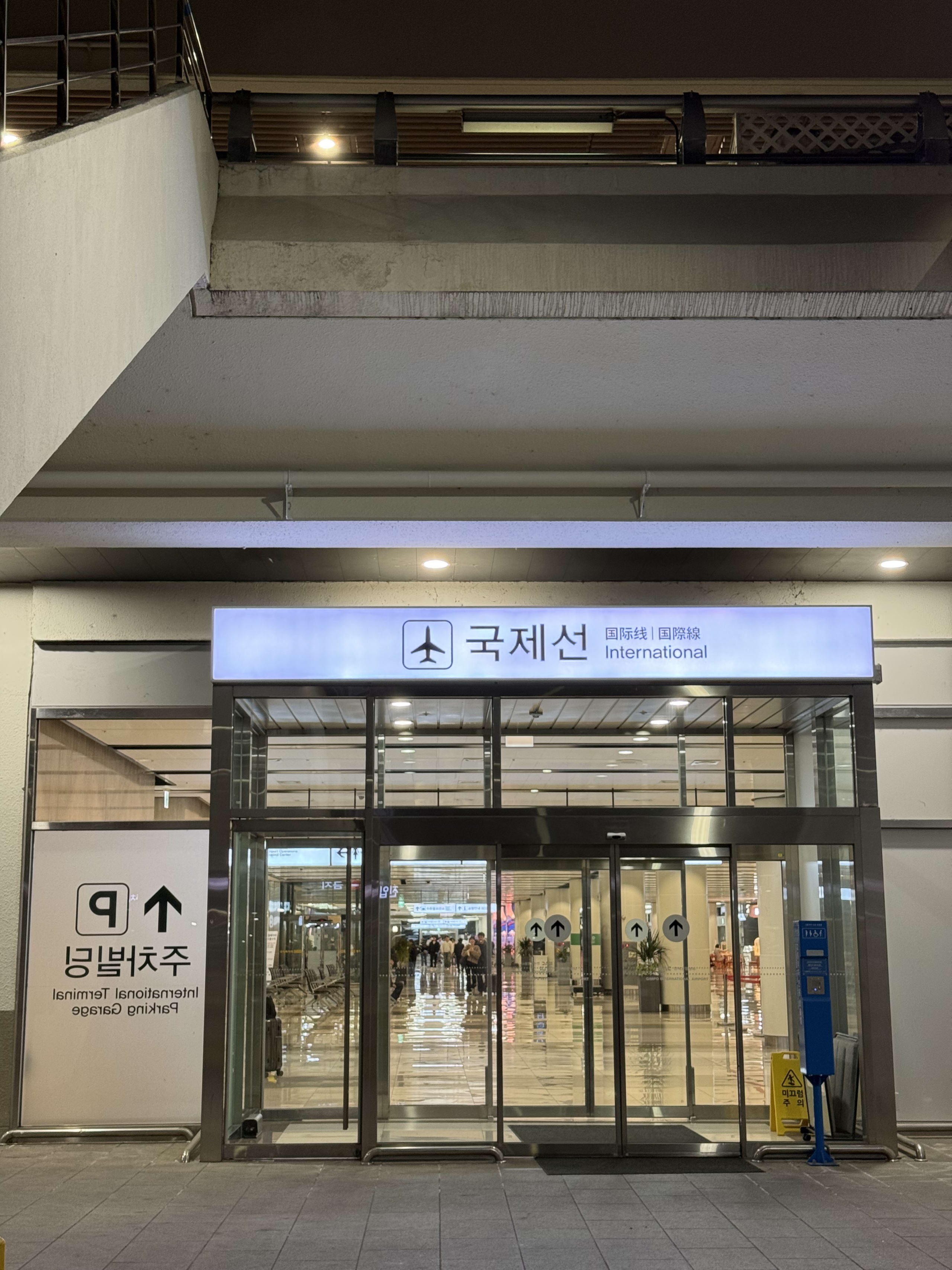 夜の金浦空港国際線の出入り口。看板が青白く光る。