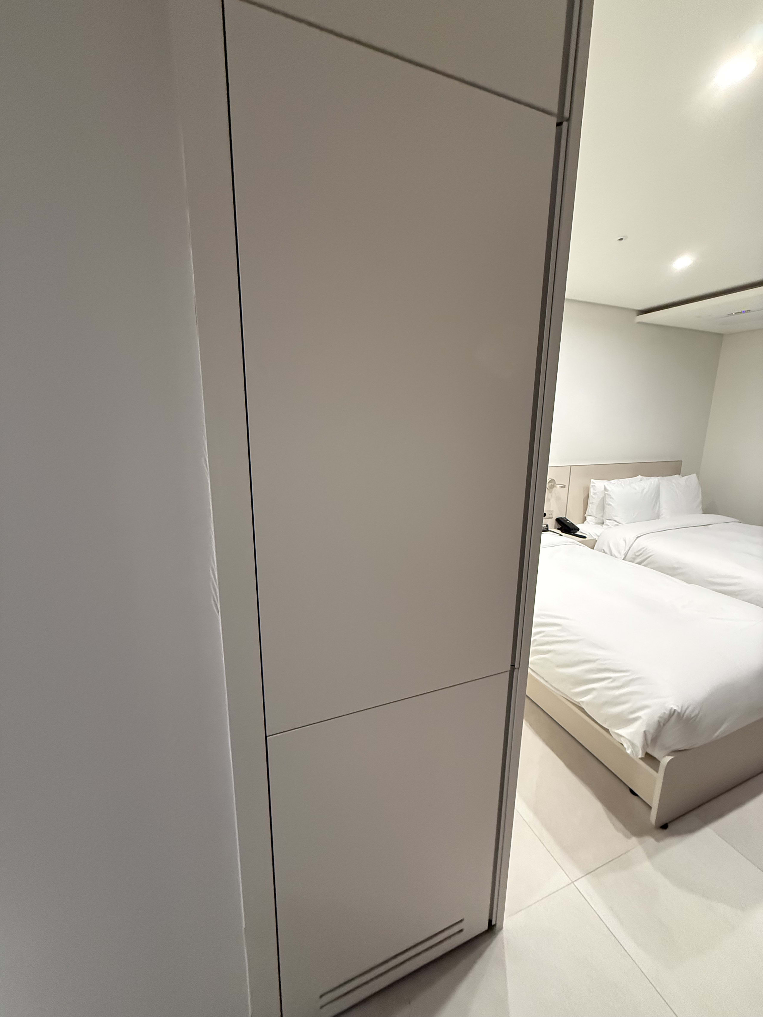 白い家電と、清潔なシーツのツインベッドがある客室。