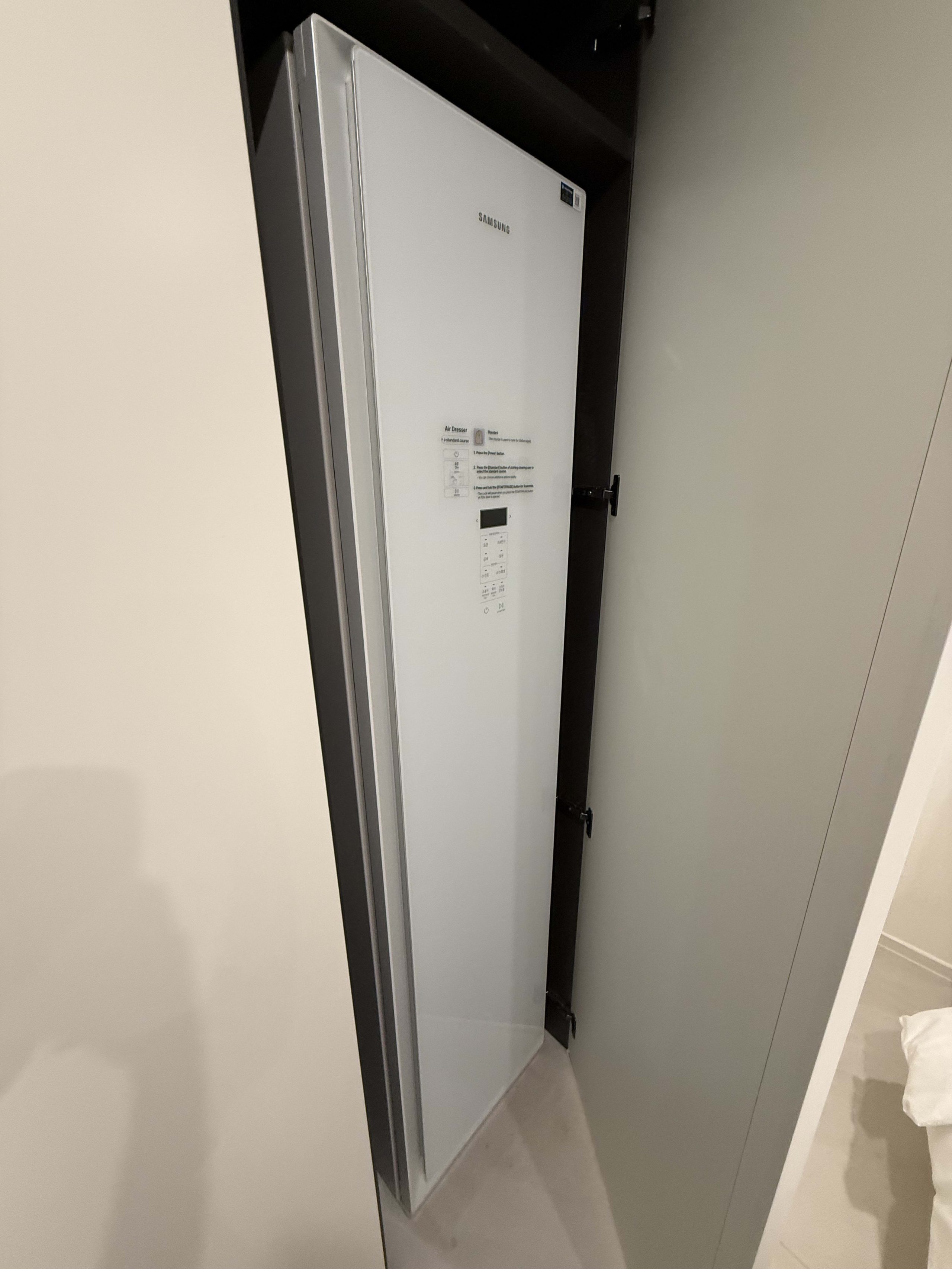 クローゼットに設置されたサムスン製の白い衣類ケア家電。