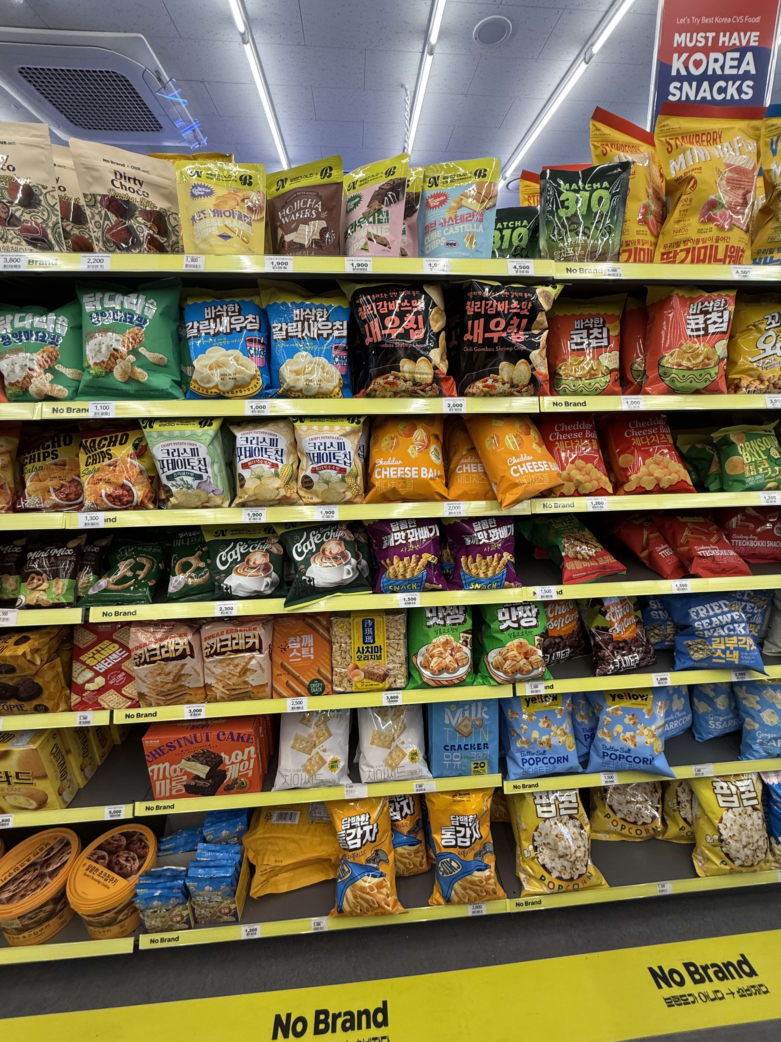 黄色い棚に陳列された韓国コンビニのスナック菓子。