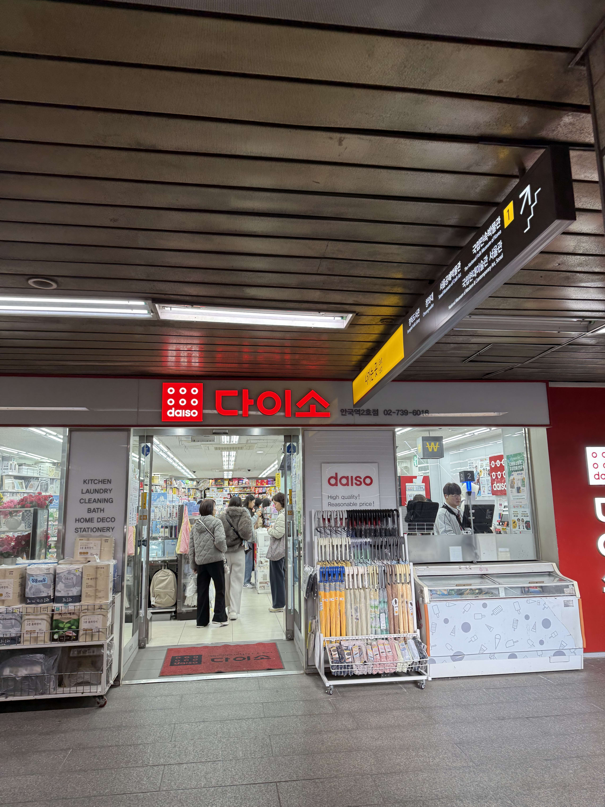 韓国の地下鉄駅構内にあるダイソー。1番出口の案内板の下、ダウンを着た客が店内へ向かう。