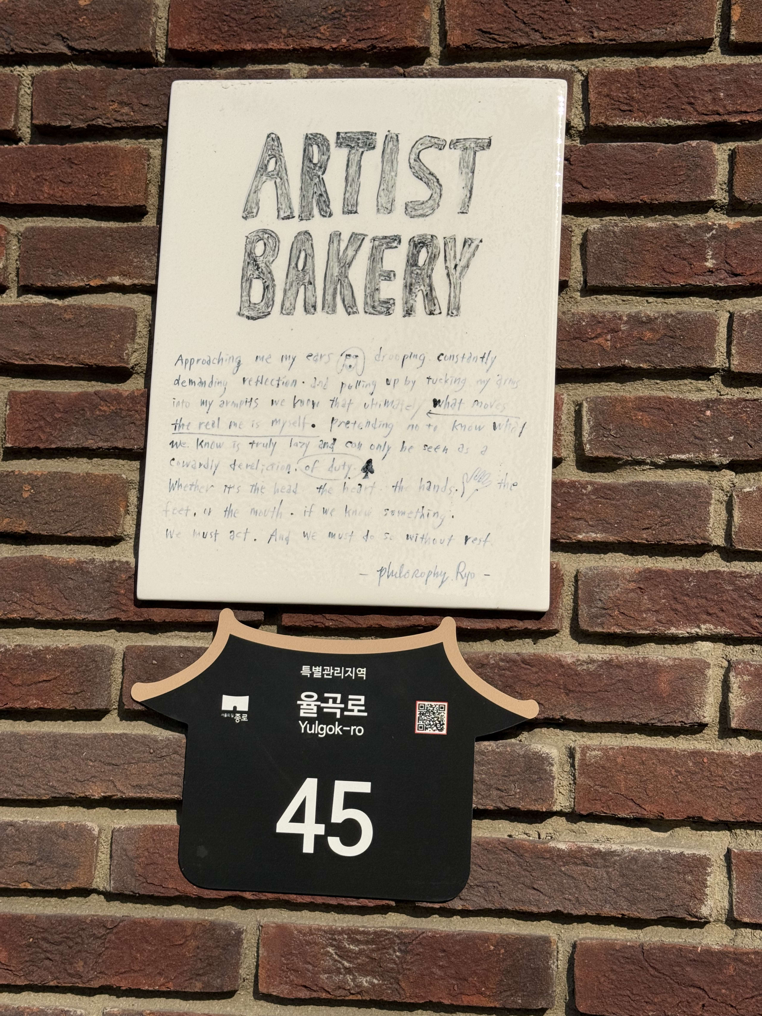 赤レンガ壁のARTIST BAKERY看板と住所プレート