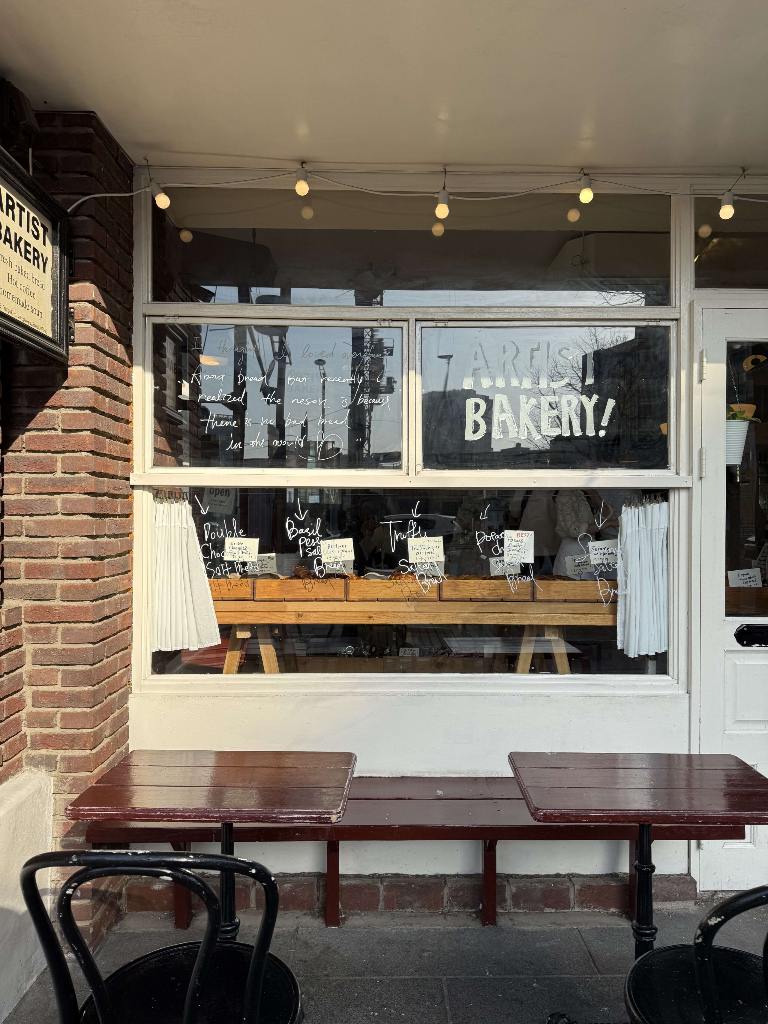 Artist Bakeryの外観と店前のベンチテーブル席。