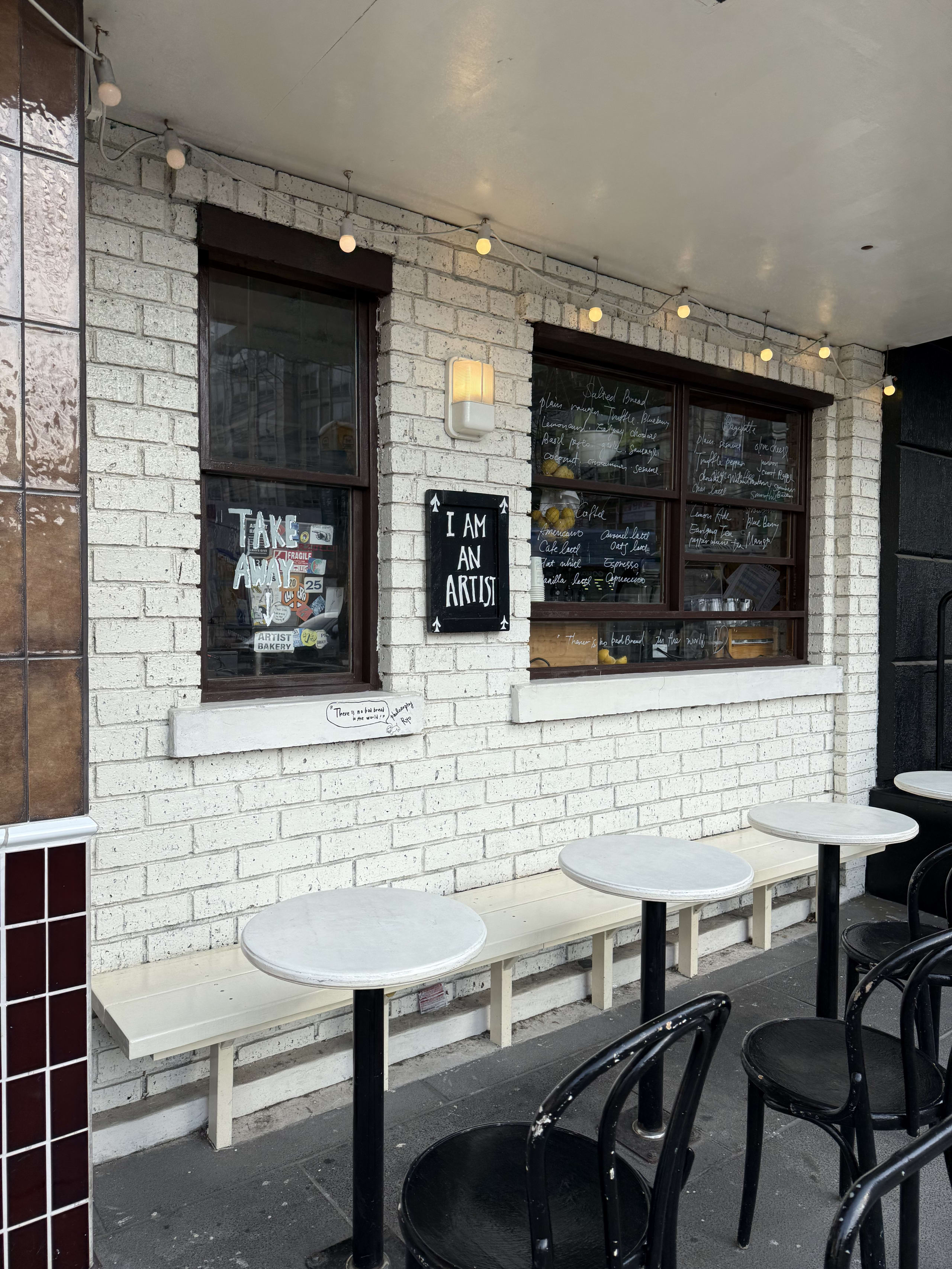 白レンガ壁と黒い窓枠が特徴的なベーカリーの外観とテラス席。