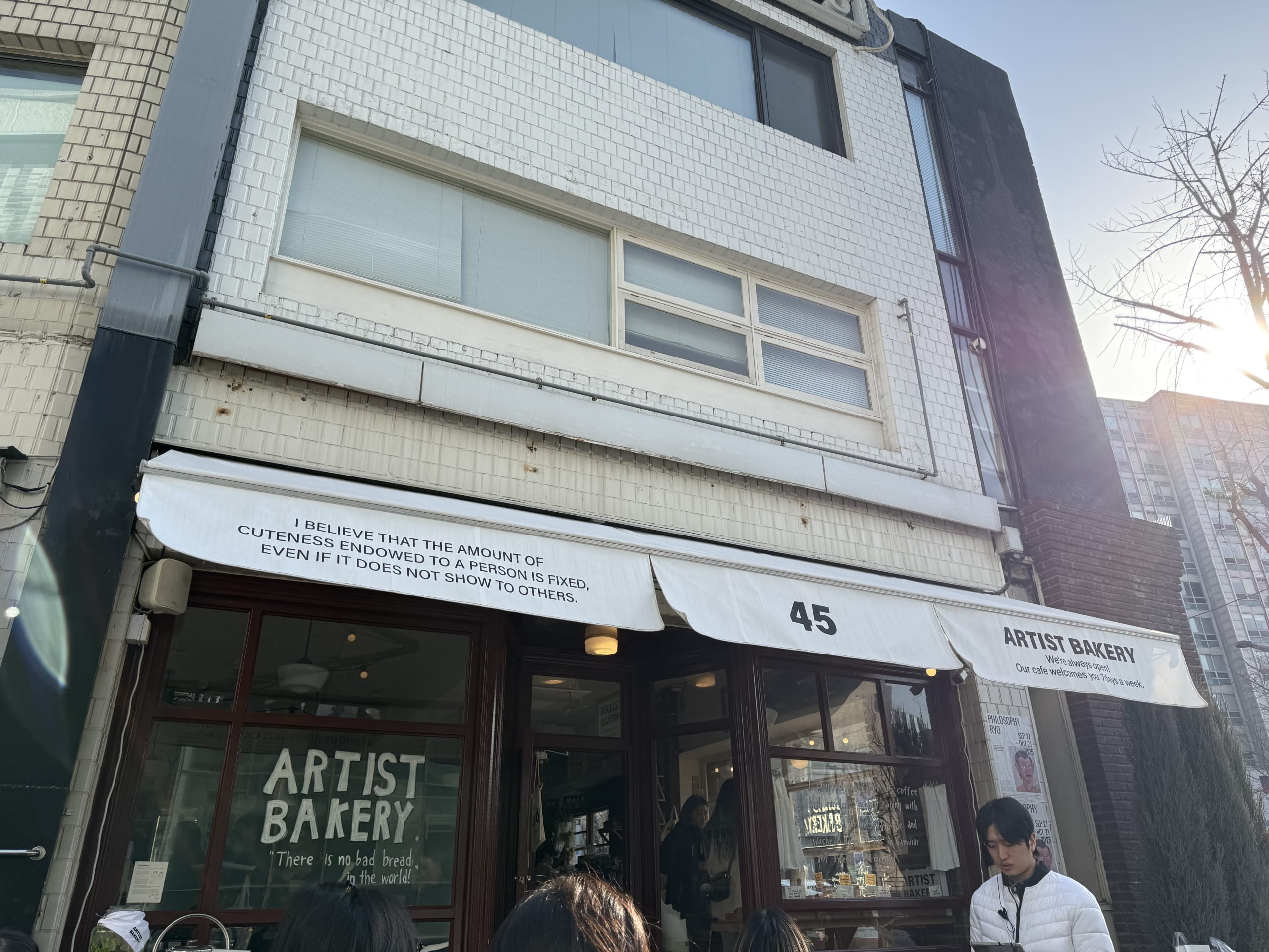 朝の光に照らされる「ARTIST BAKERY」の外観と人々。