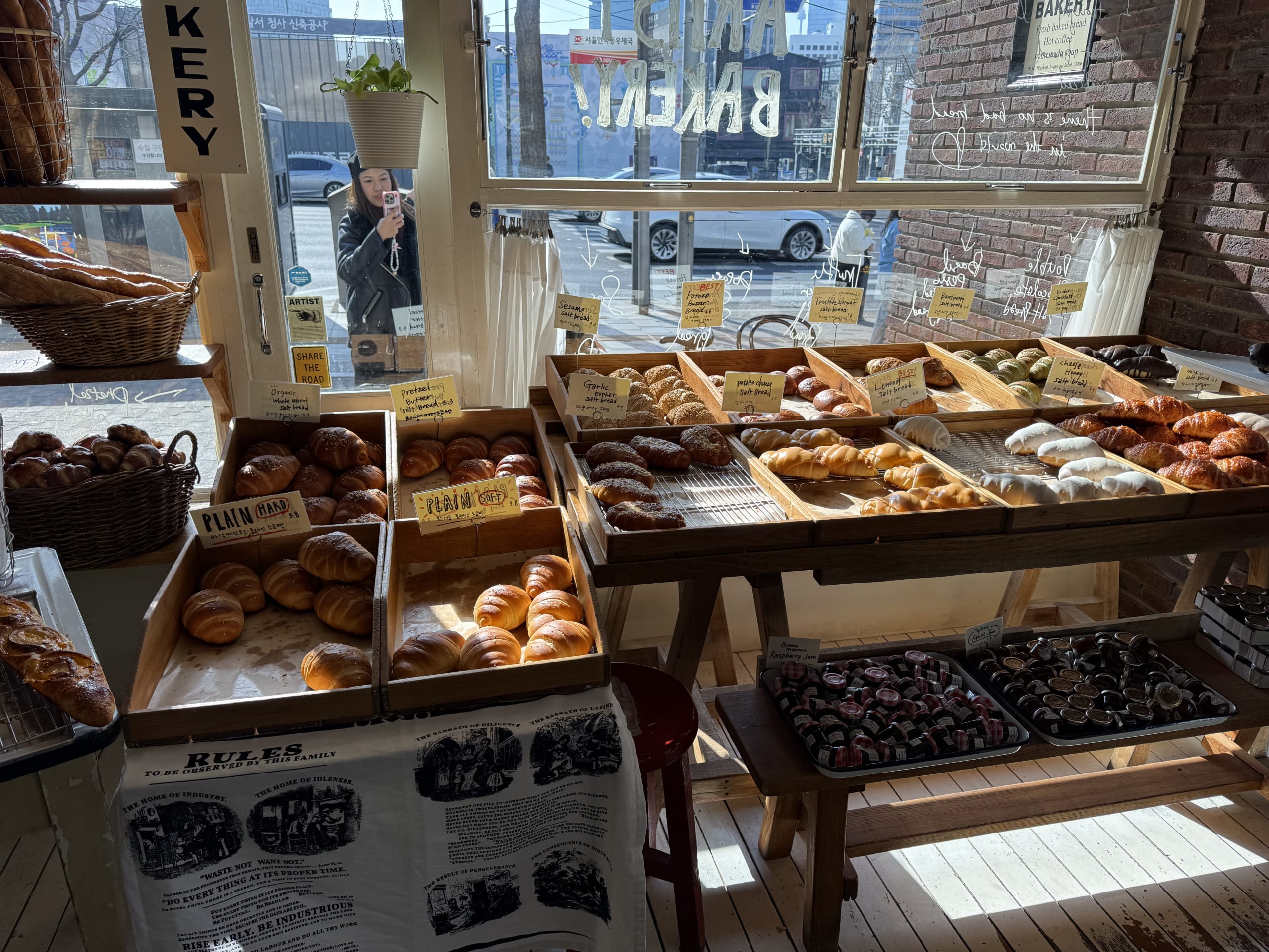 窓からの朝日が差し込むArtist Bakeryの店内。木箱に様々な種類のパンが並ぶ。