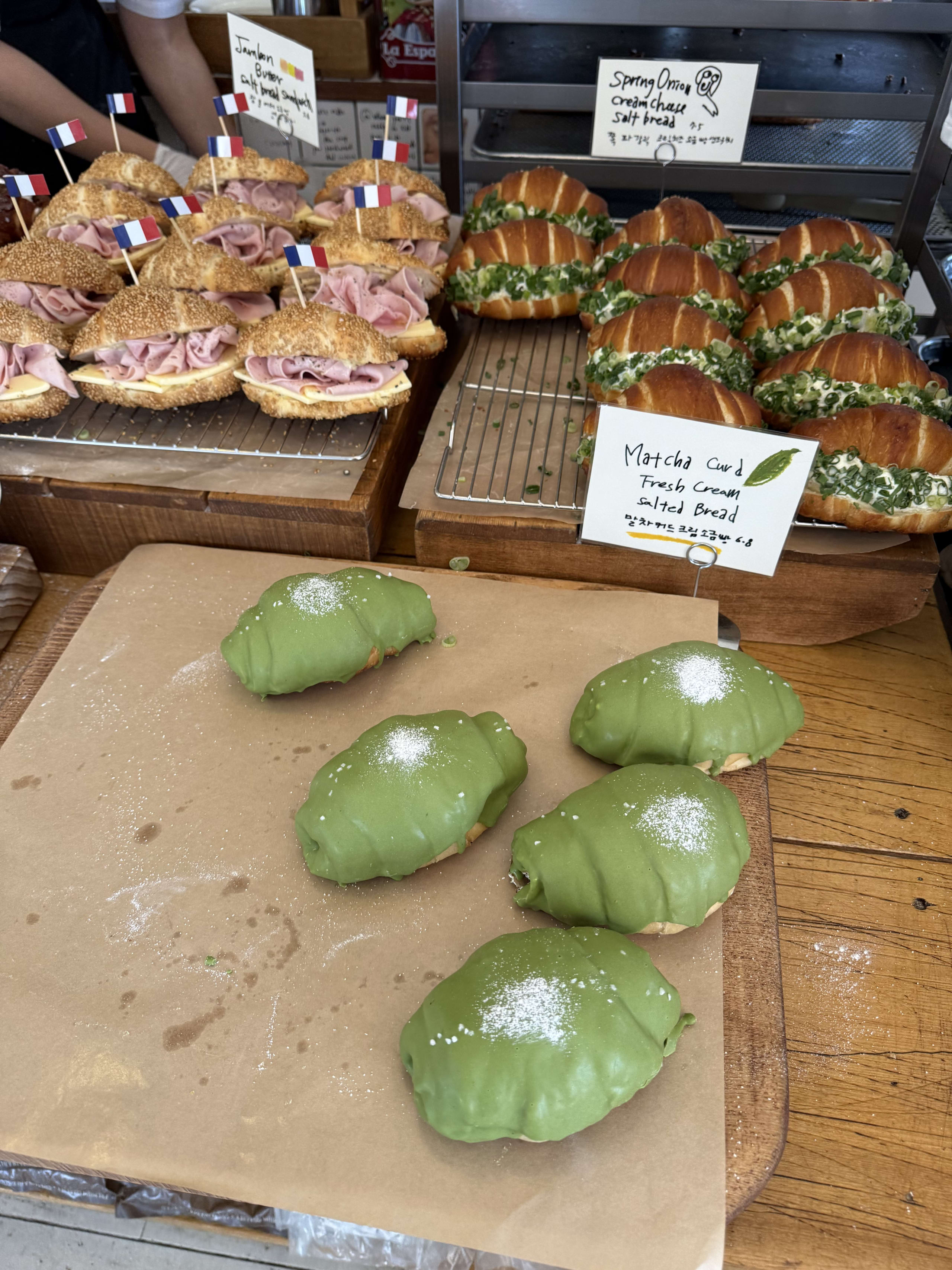 抹茶塩パンと惣菜系塩パンが並ぶパン屋の陳列棚。