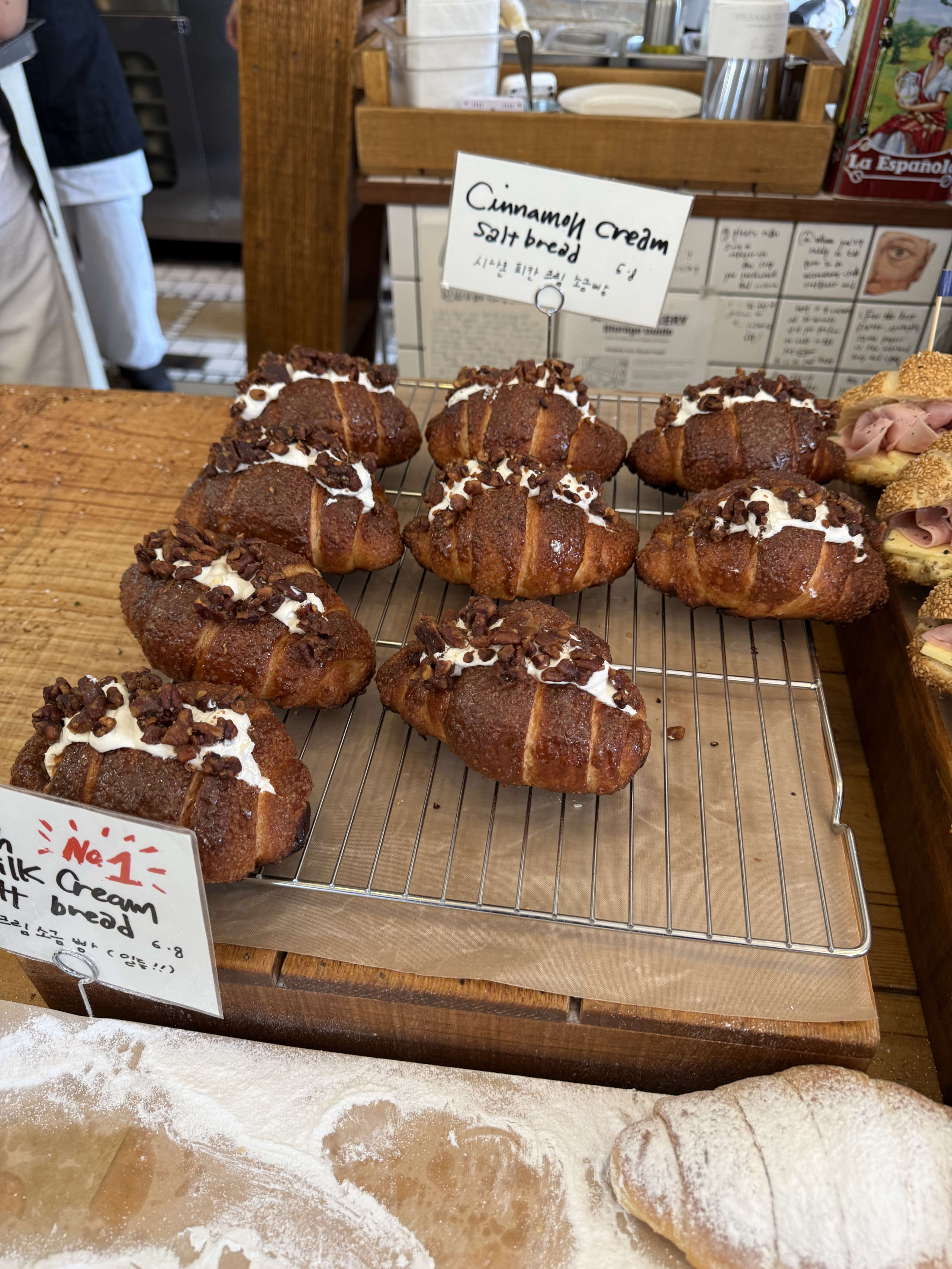 ラックに並ぶシナモンクリーム塩パン。白いクリームとナッツが乗っている。