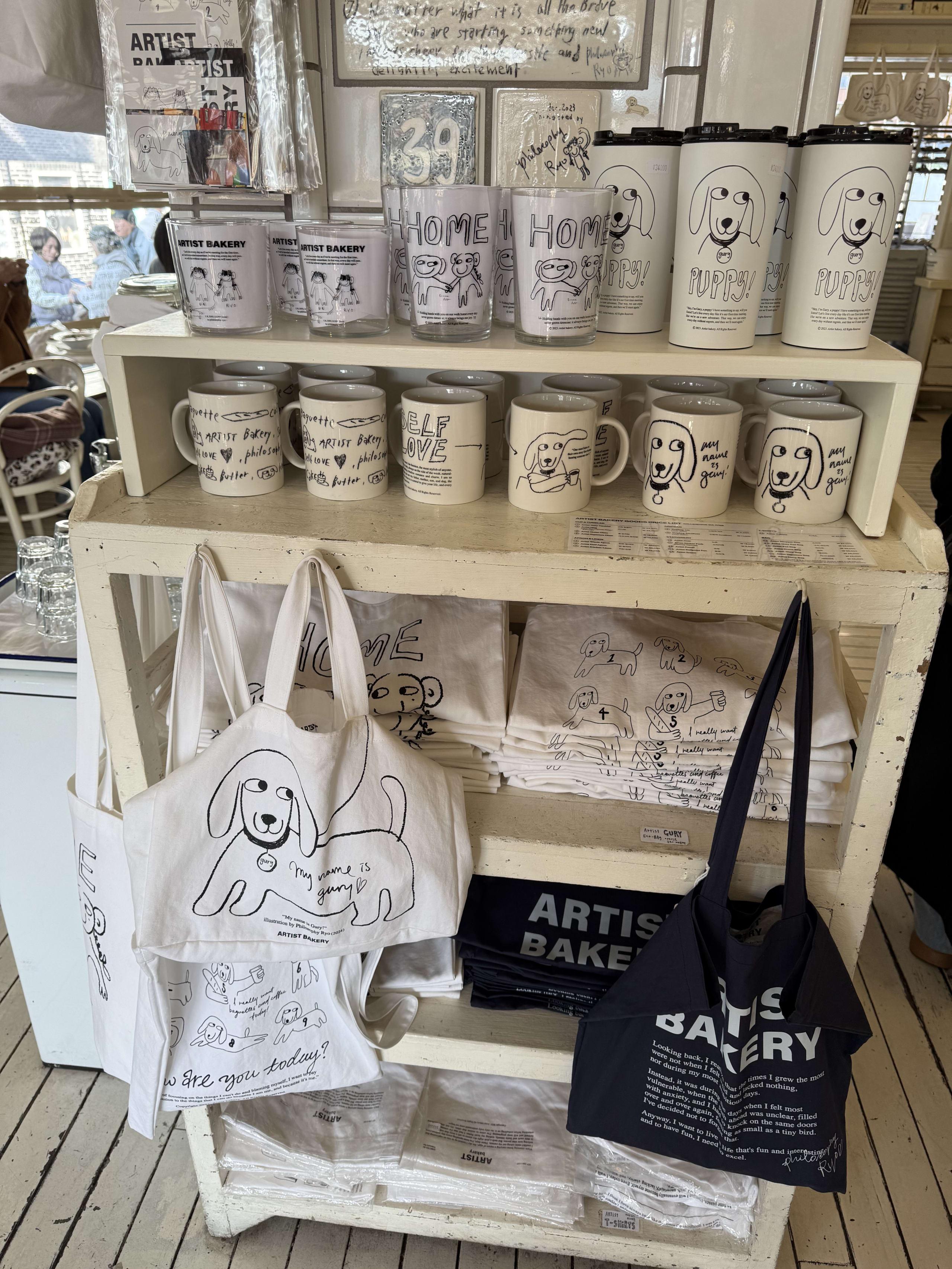 犬のイラストが描かれたマグカップやエコバッグ等のグッズ。