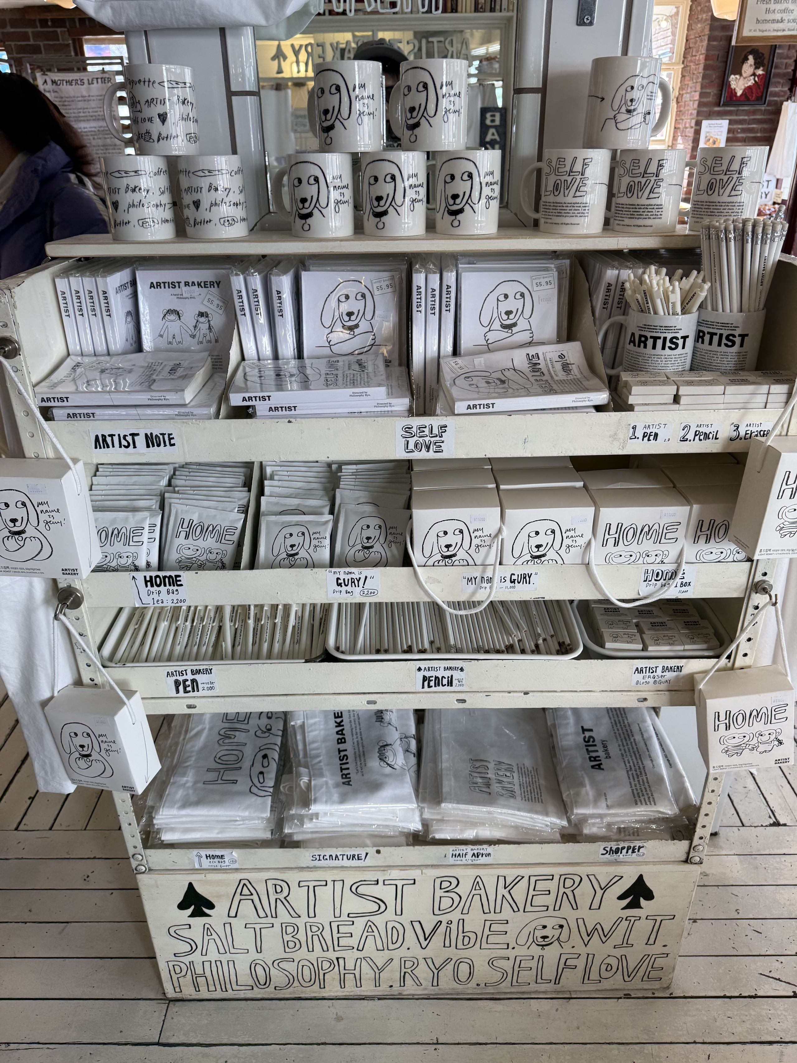 白い棚に並ぶ犬のイラスト入りのオリジナルグッズ。