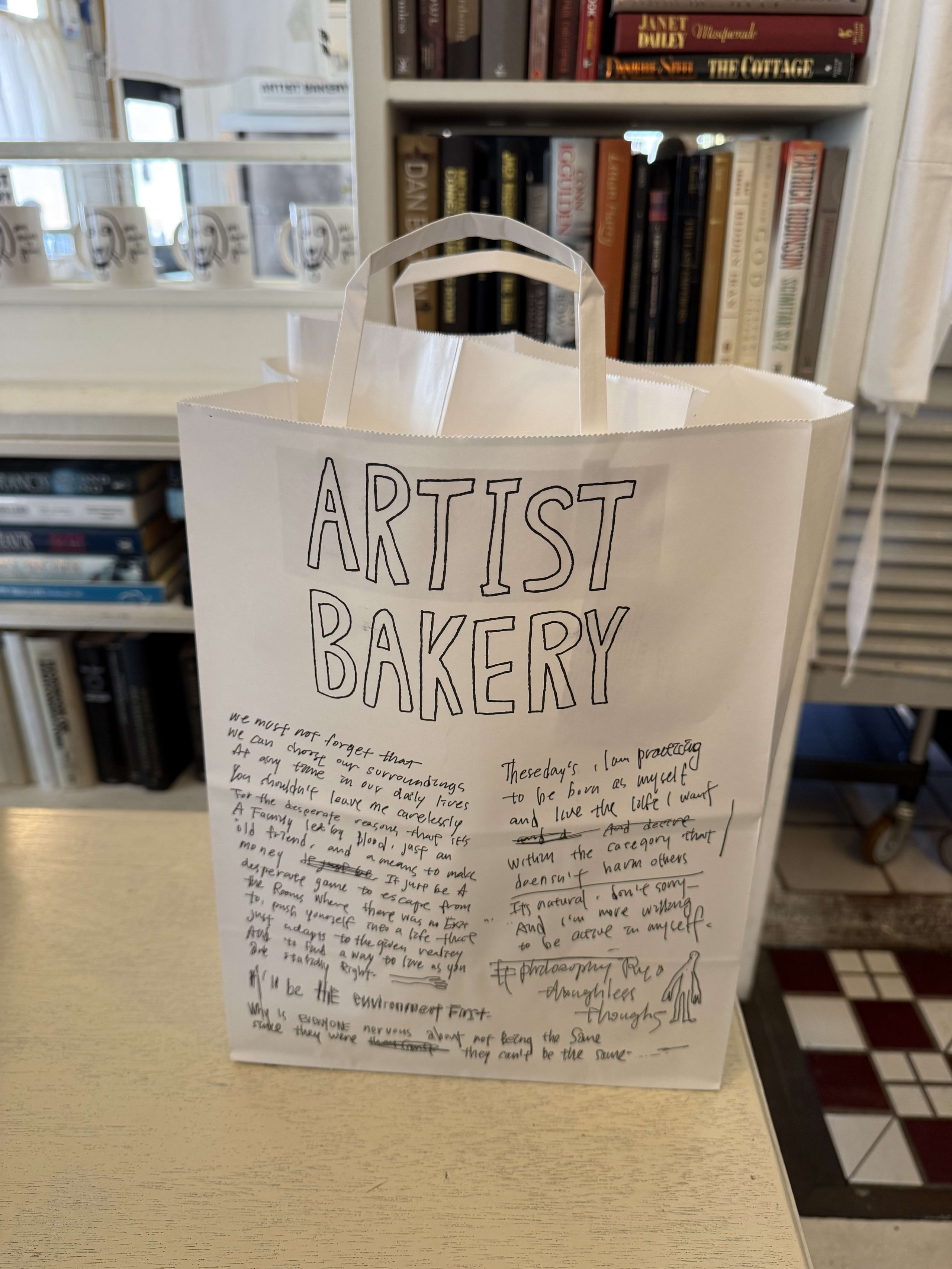 カウンターに置かれた「ARTIST BAKERY」の手書き風ロゴ入り白い紙袋。