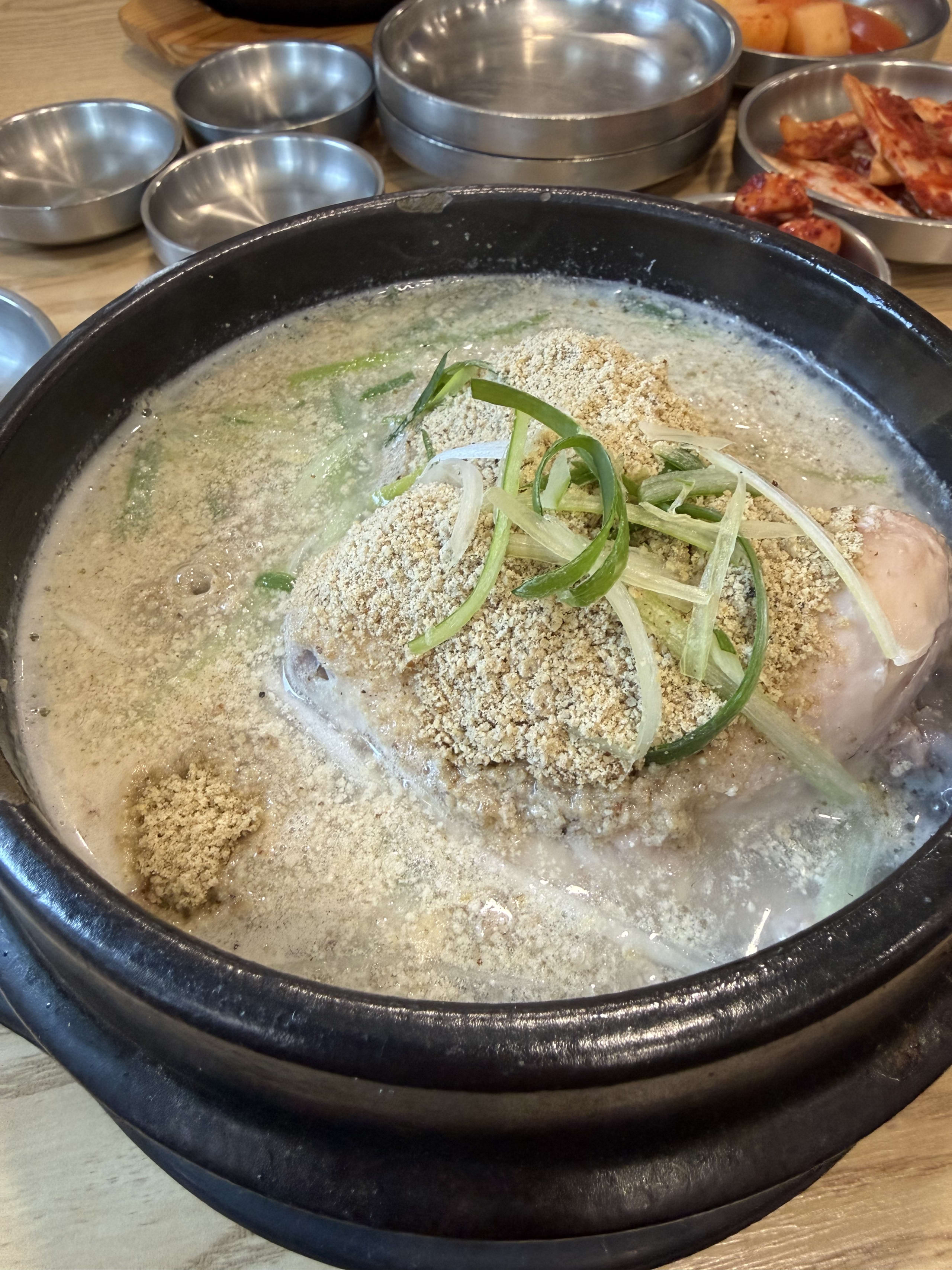 エゴマ粉とネギが乗った土鍋で煮立つ参鶏湯。