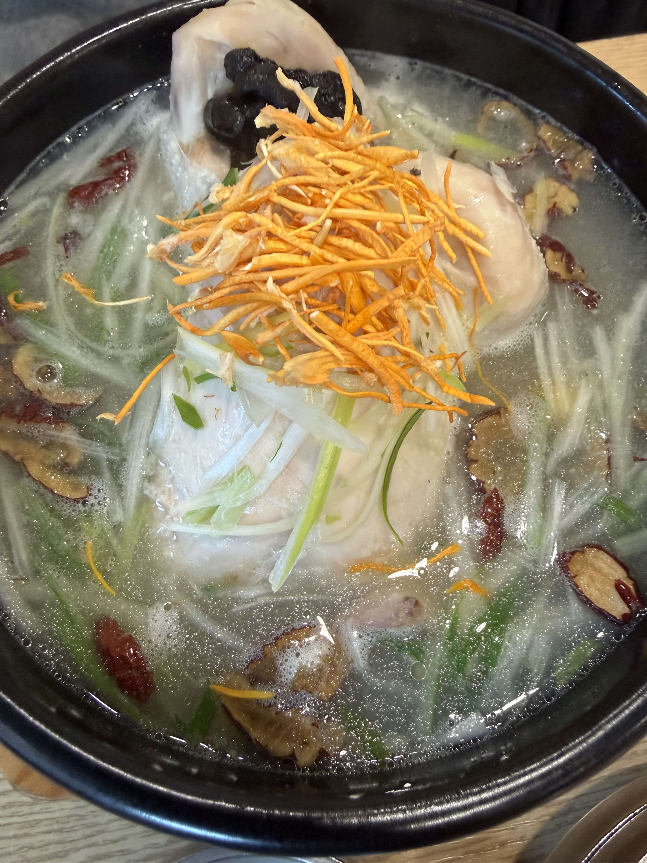 土鍋で煮え立つ参鶏湯。丸鶏にネギやナツメが乗る。