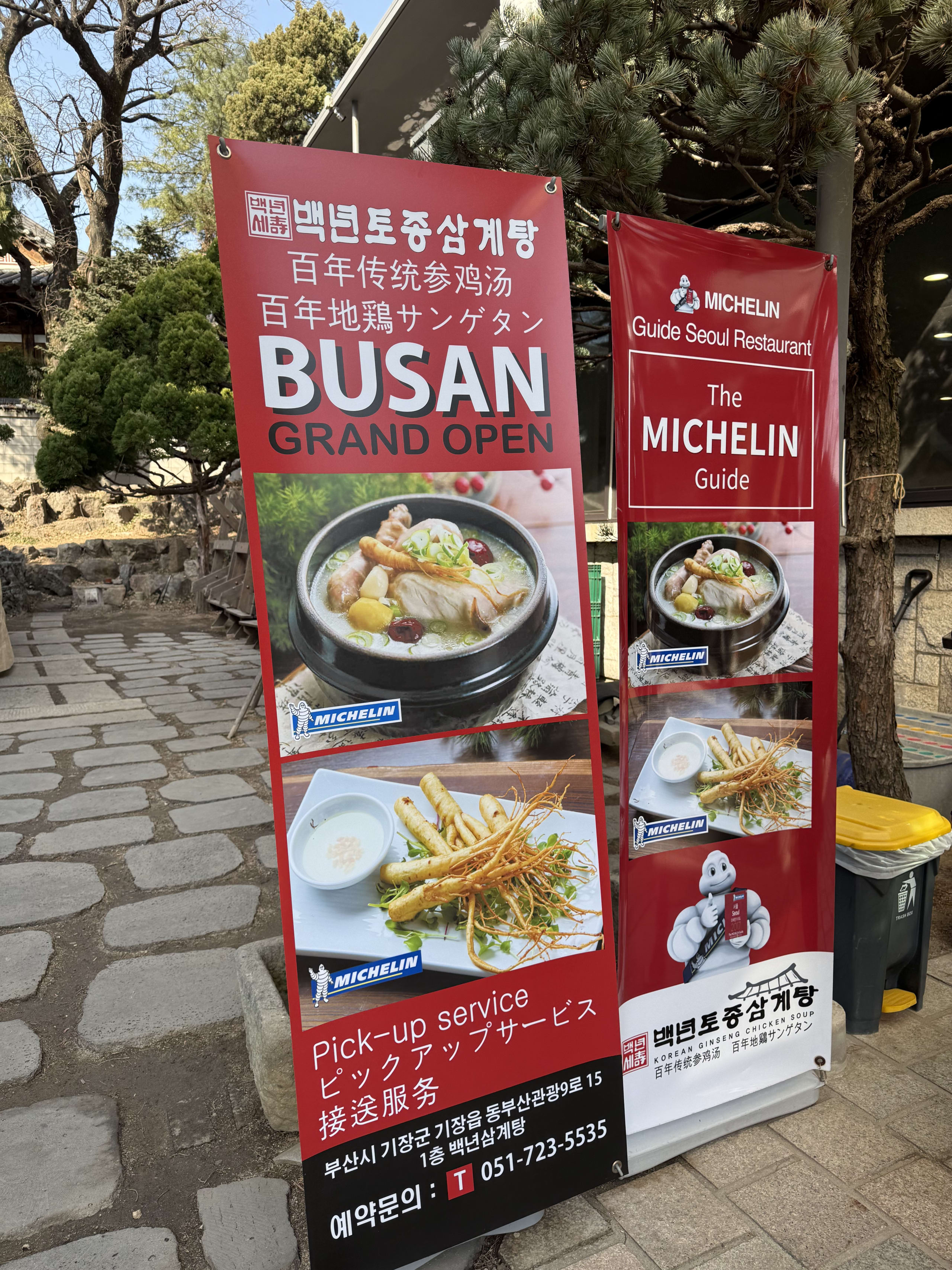 ミシュランガイド掲載を示す「百年地鶏サンゲタン」の赤い看板と石畳のアプローチ。