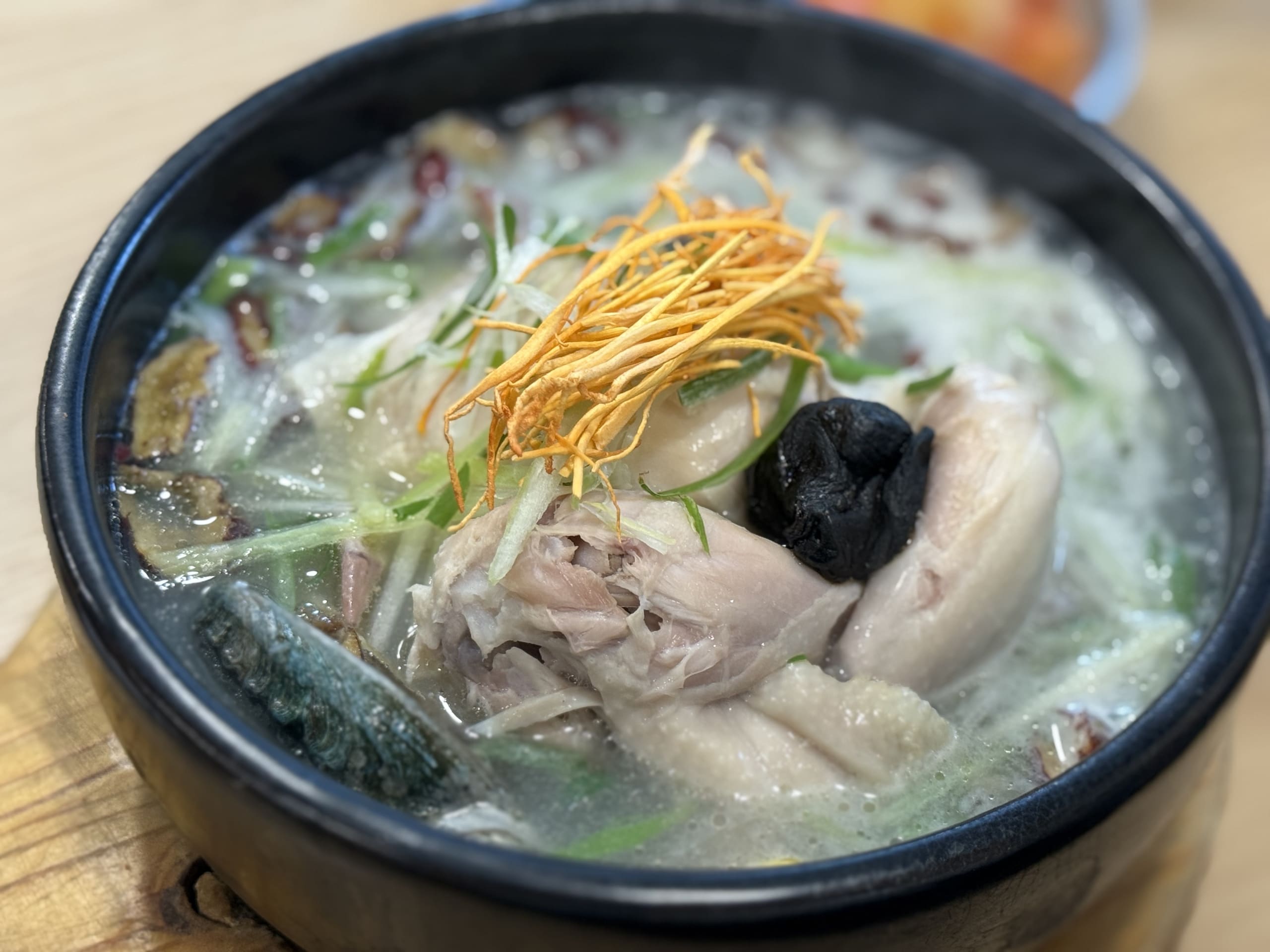 黒い土鍋で煮立つ、アワビやキノコが乗った熱々の参鶏湯。