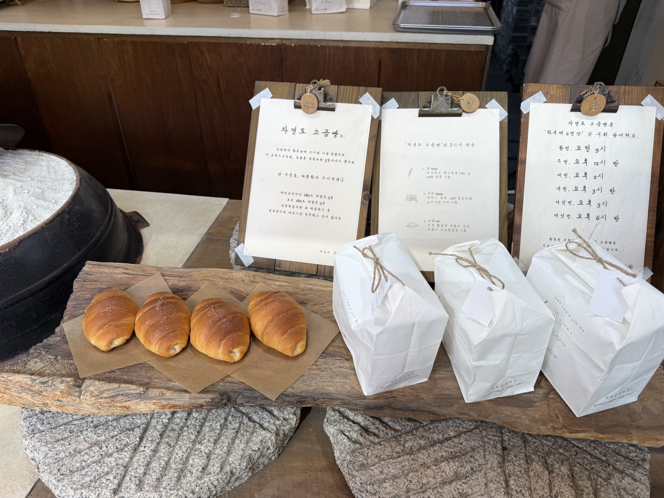 木の板に並ぶ4つの塩パンと白い紙袋。
