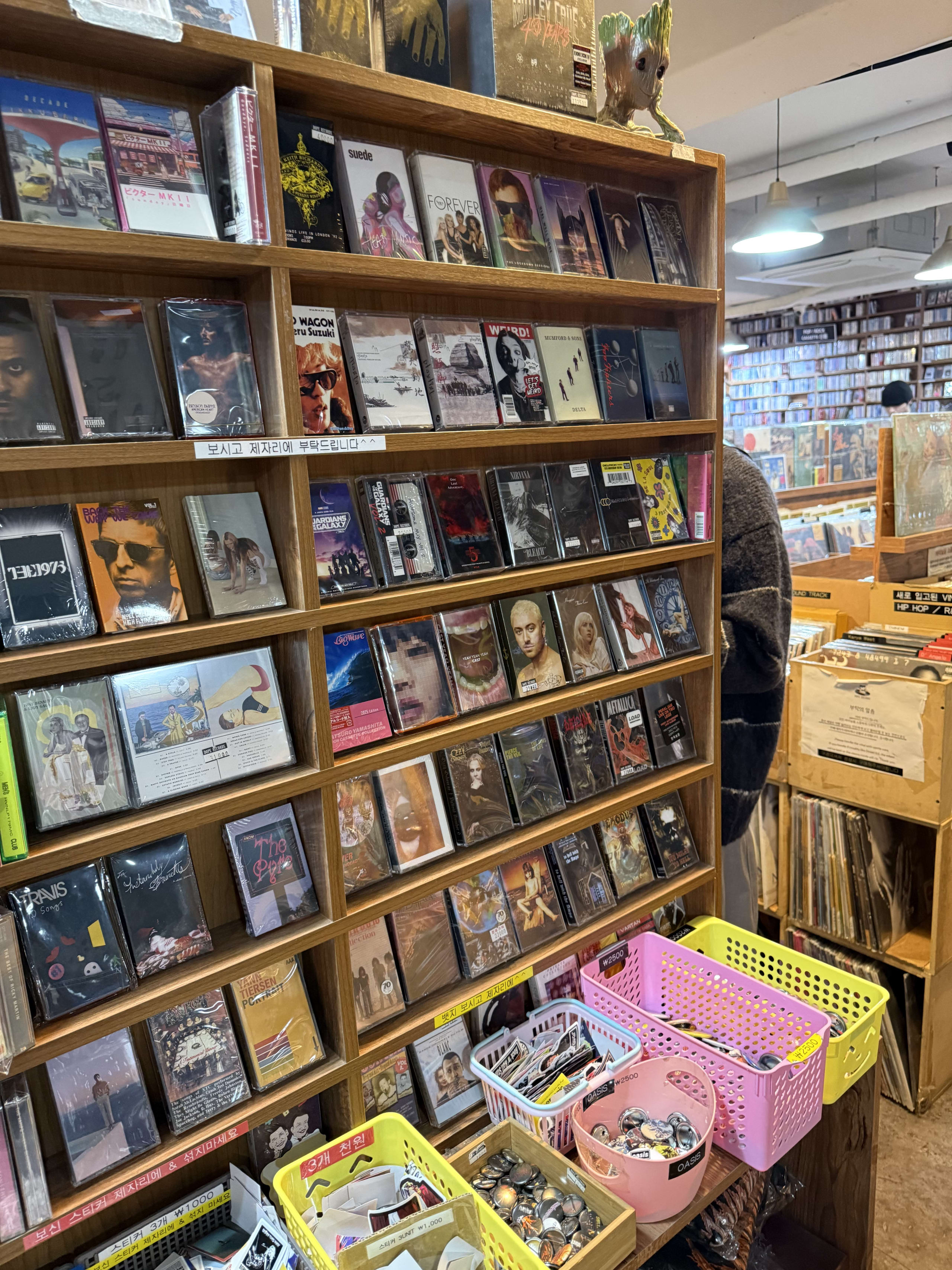 木製棚に並ぶカセットテープと手前の小物カゴ。