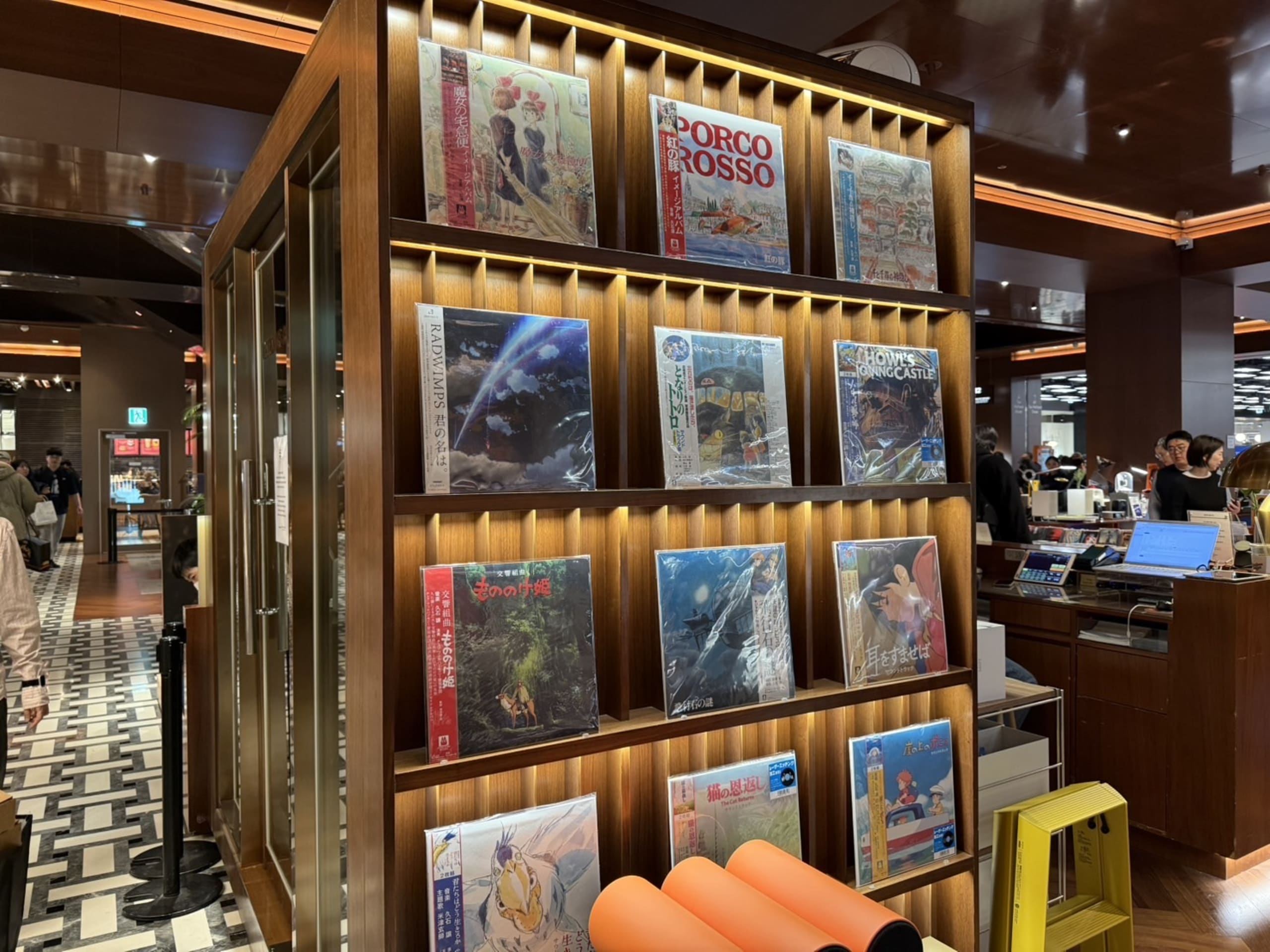 間接照明に照らされた木製ラックに並ぶ日本アニメのレコード。