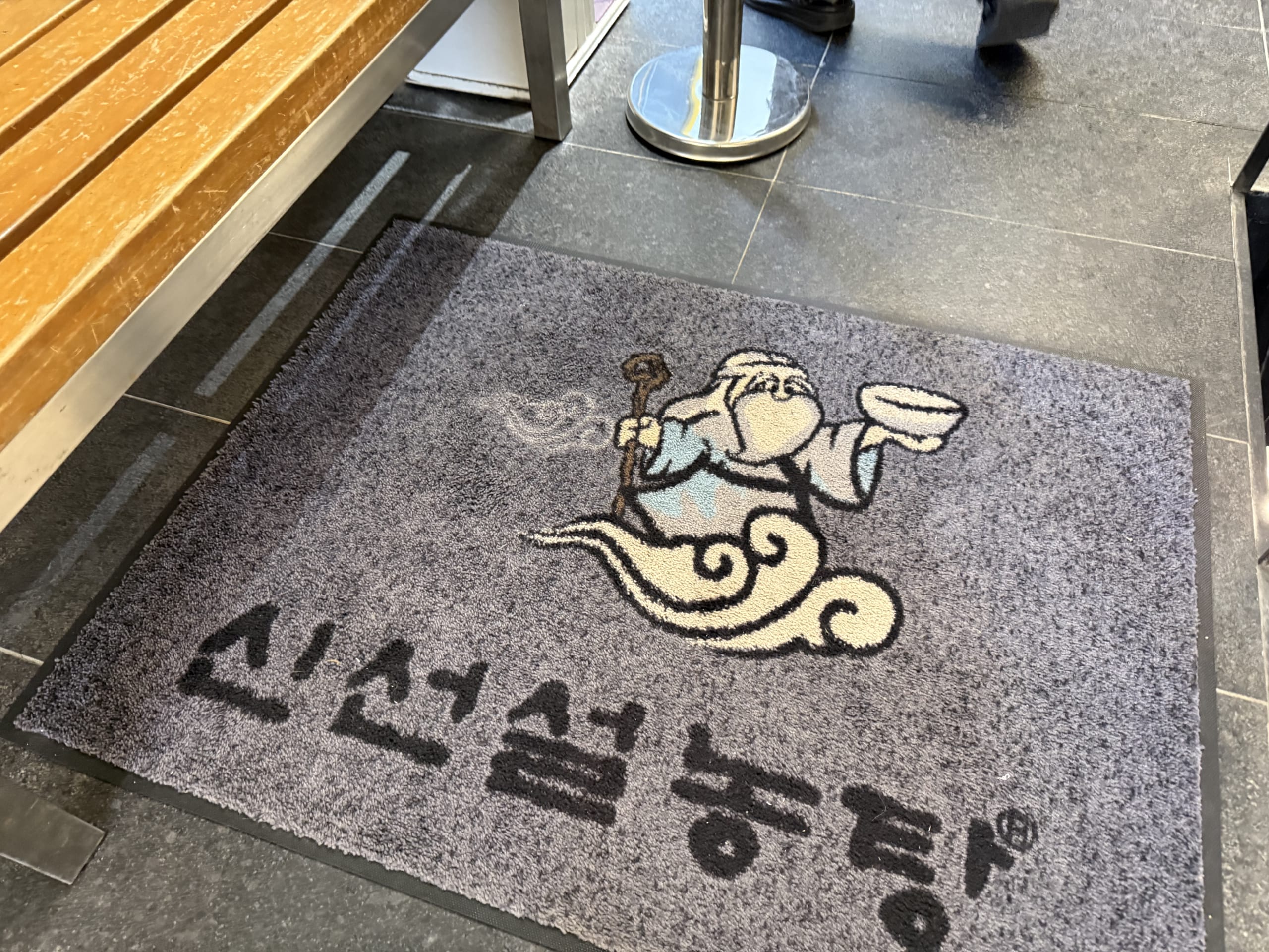 雲に乗る仙人とハングルが描かれた神仙ソルロンタン入り口のマット。