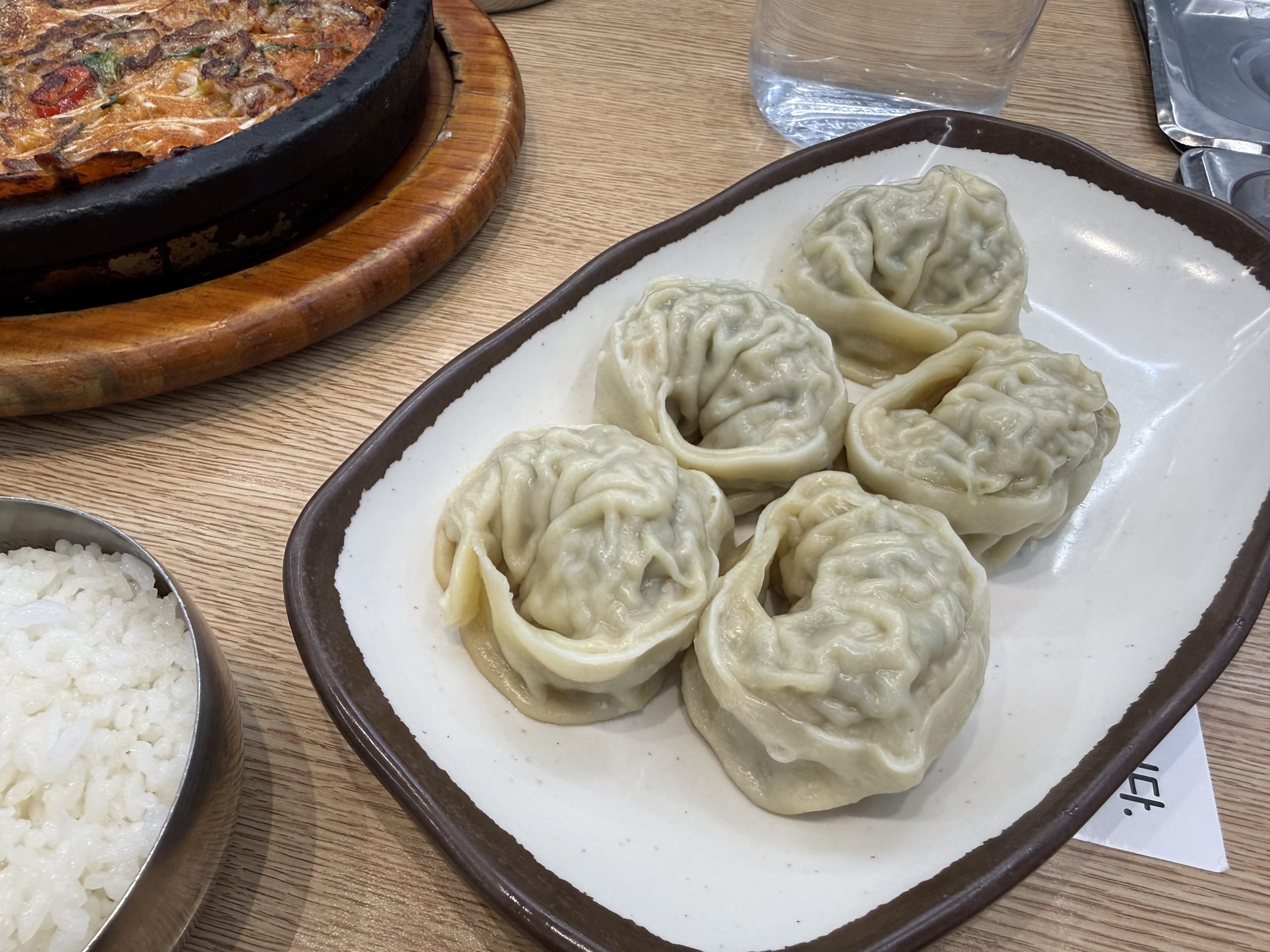 白い皿に盛られた5つのマンドゥとチヂミ、白ご飯。