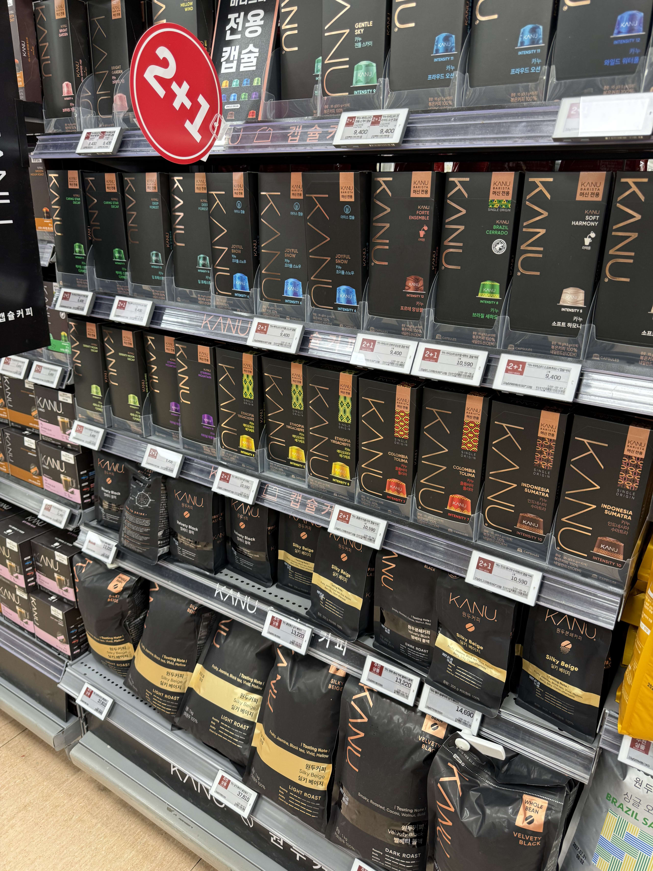 棚に並ぶ黒と金のKANUコーヒーと2+1の赤いPOP。