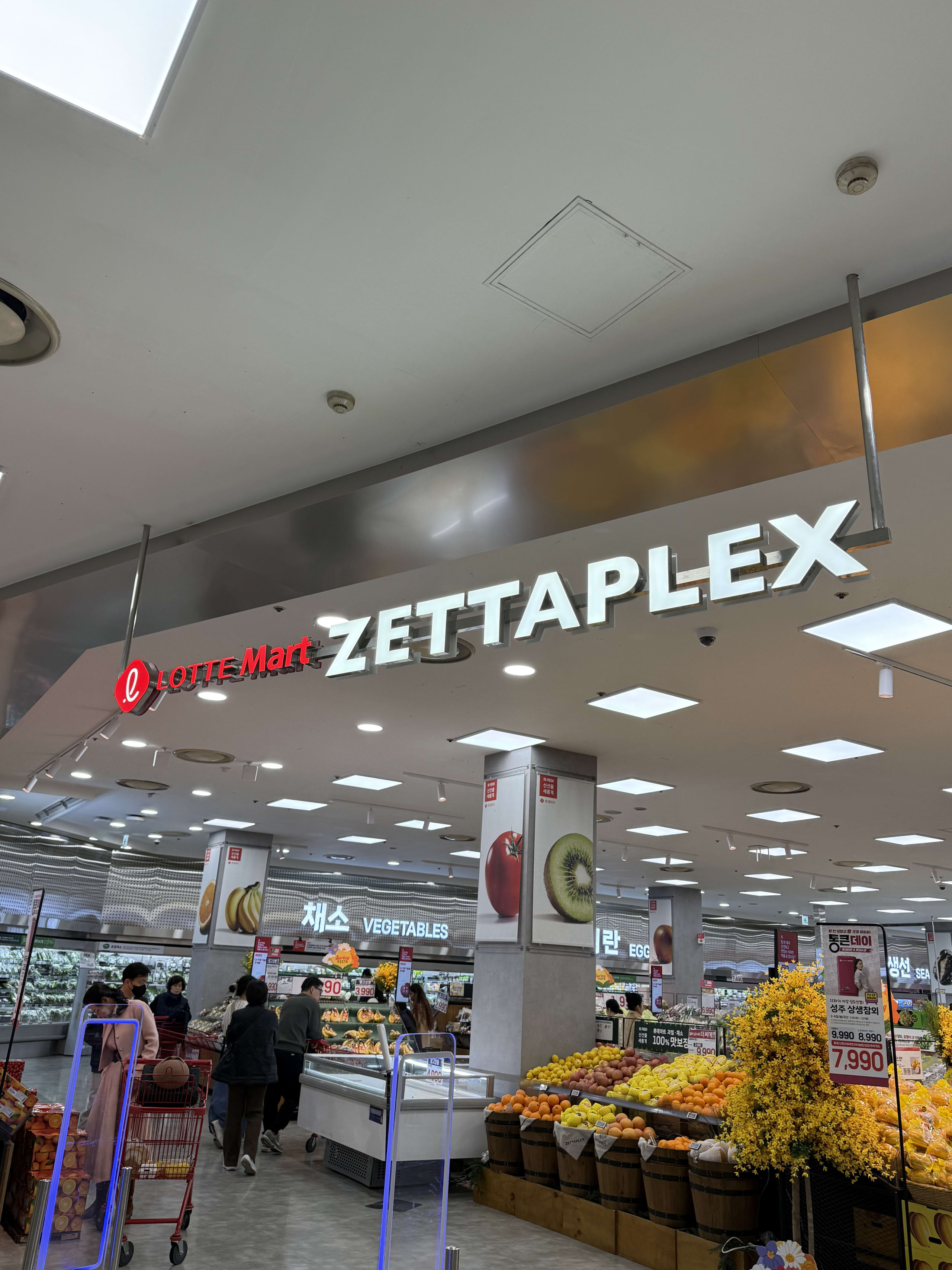 ロッテマートZETTAPLEXの入口。青果売場と買い物客。