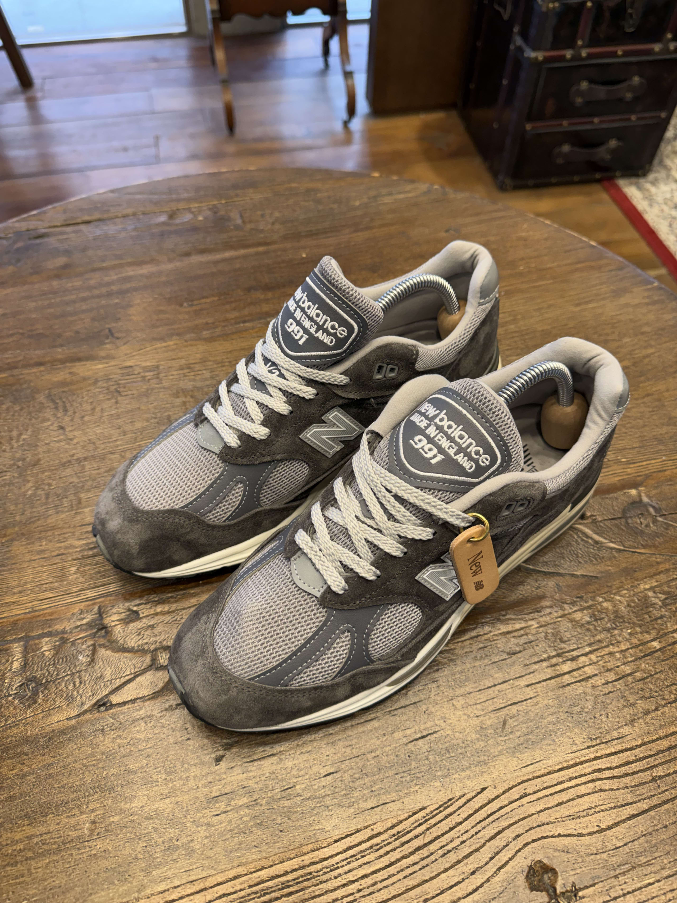 木製机上のグレーのニューバランス991。