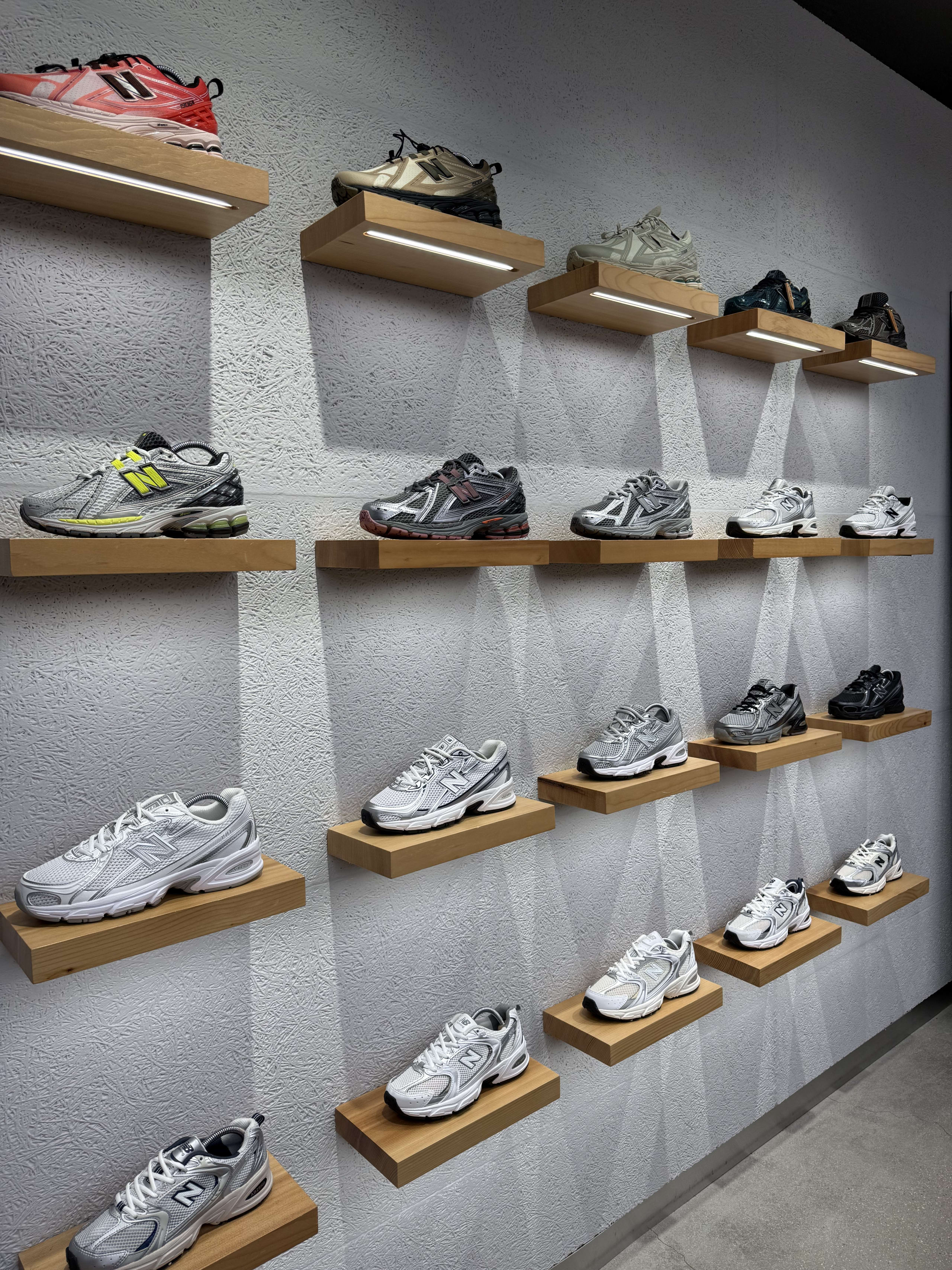 聖水ニューバランス店の木製棚に並ぶ靴。