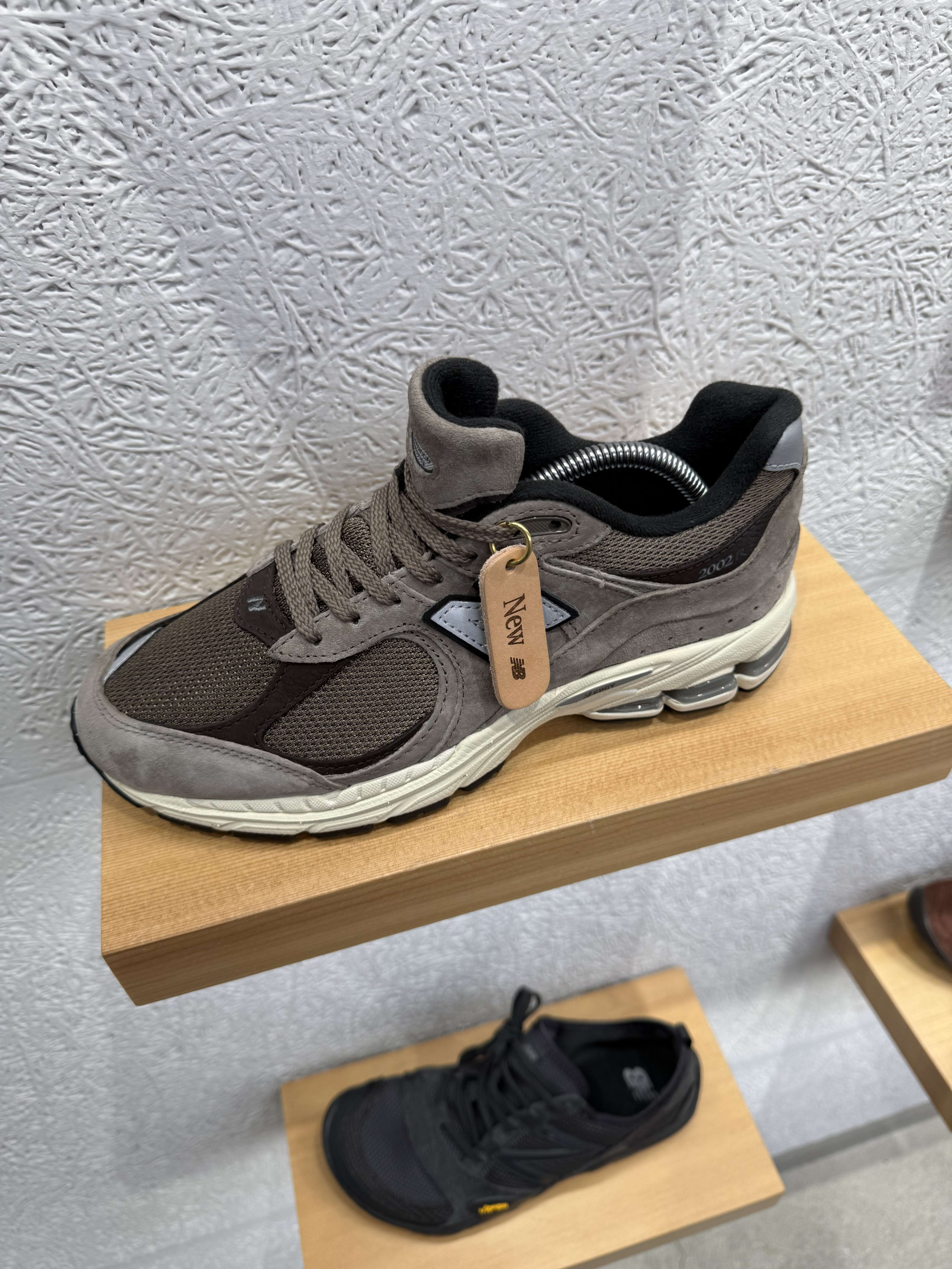木の棚に展示されたブラウングレーのニューバランス2002R。