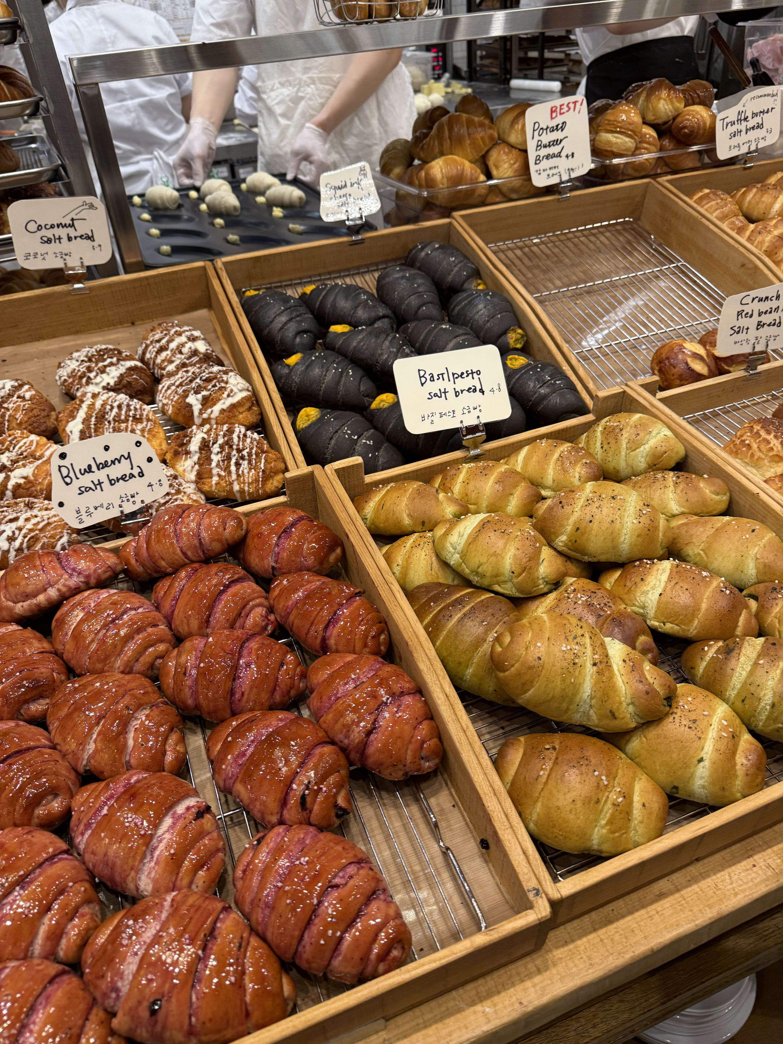 木製トレイに並ぶ色鮮やかで種類豊富な塩パンと奥のキッチン。