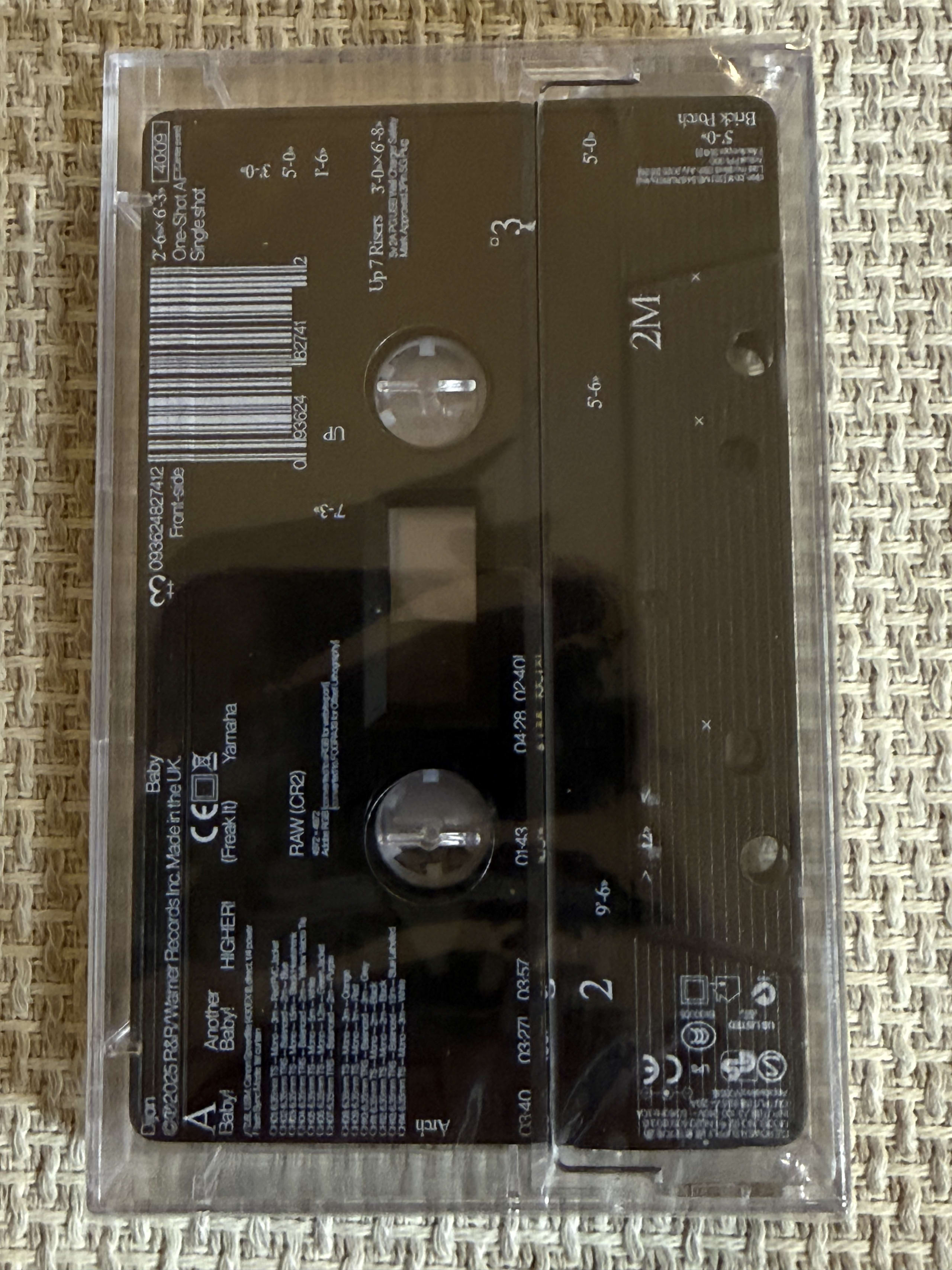 布の上に置かれた透明ケース入りDijonのカセットテープ『Baby』。