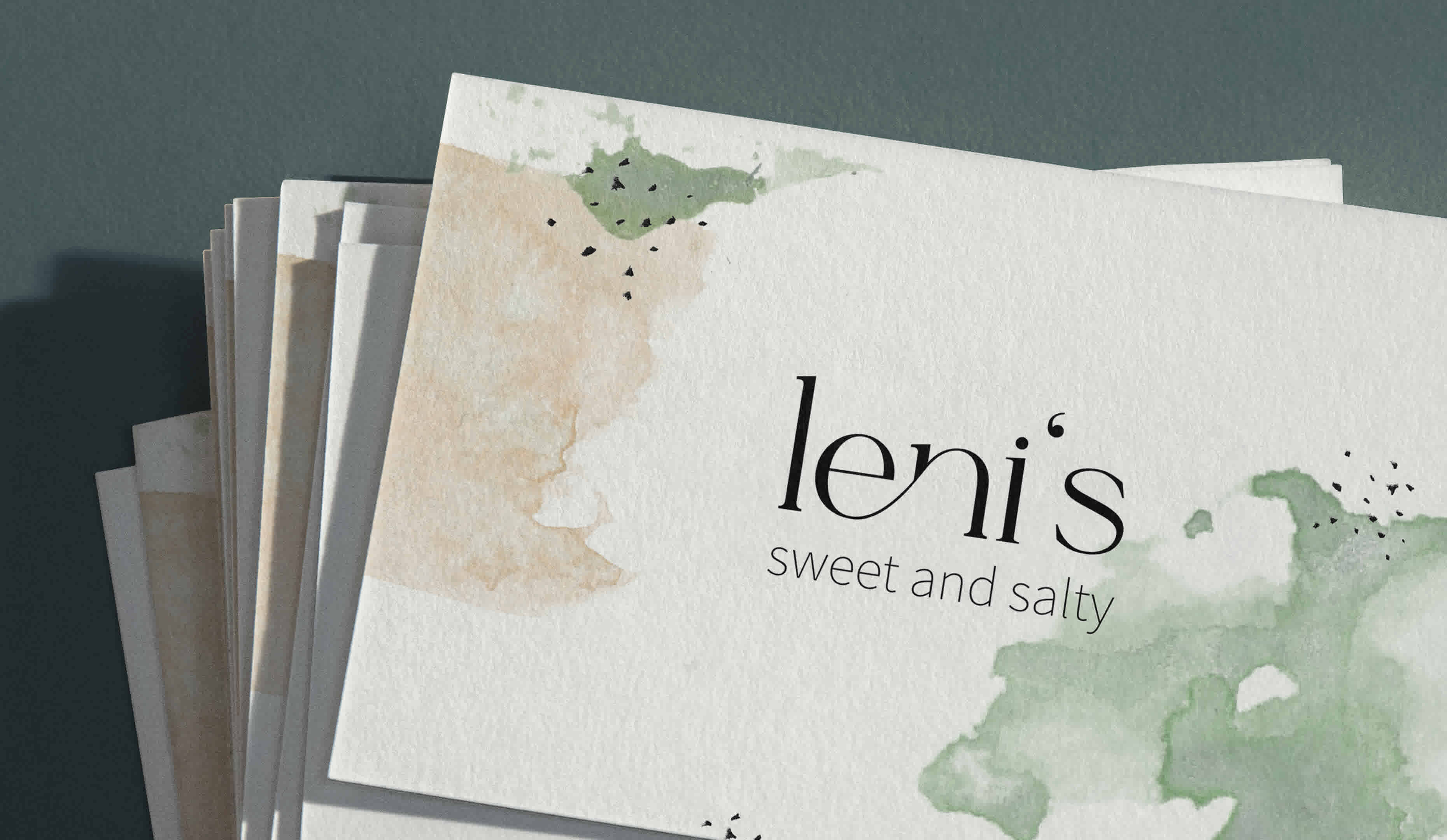 The close-up of Leni's business cards can be seen. The serif font is accentuated by elements in watercolors.