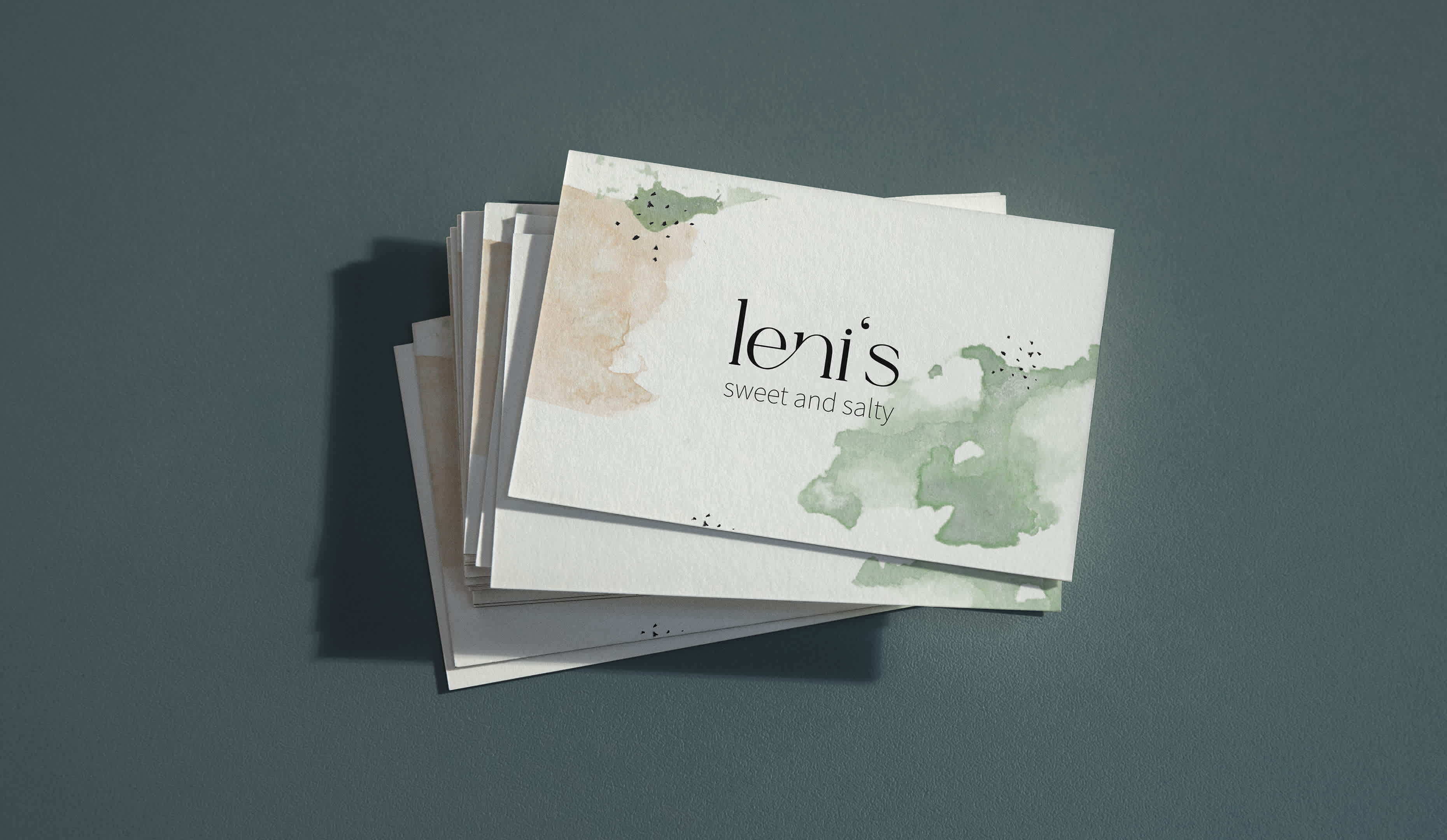 A stack of business cards with the leni's logo. The business cards show the freshness and nature of food through a watercolor design style.