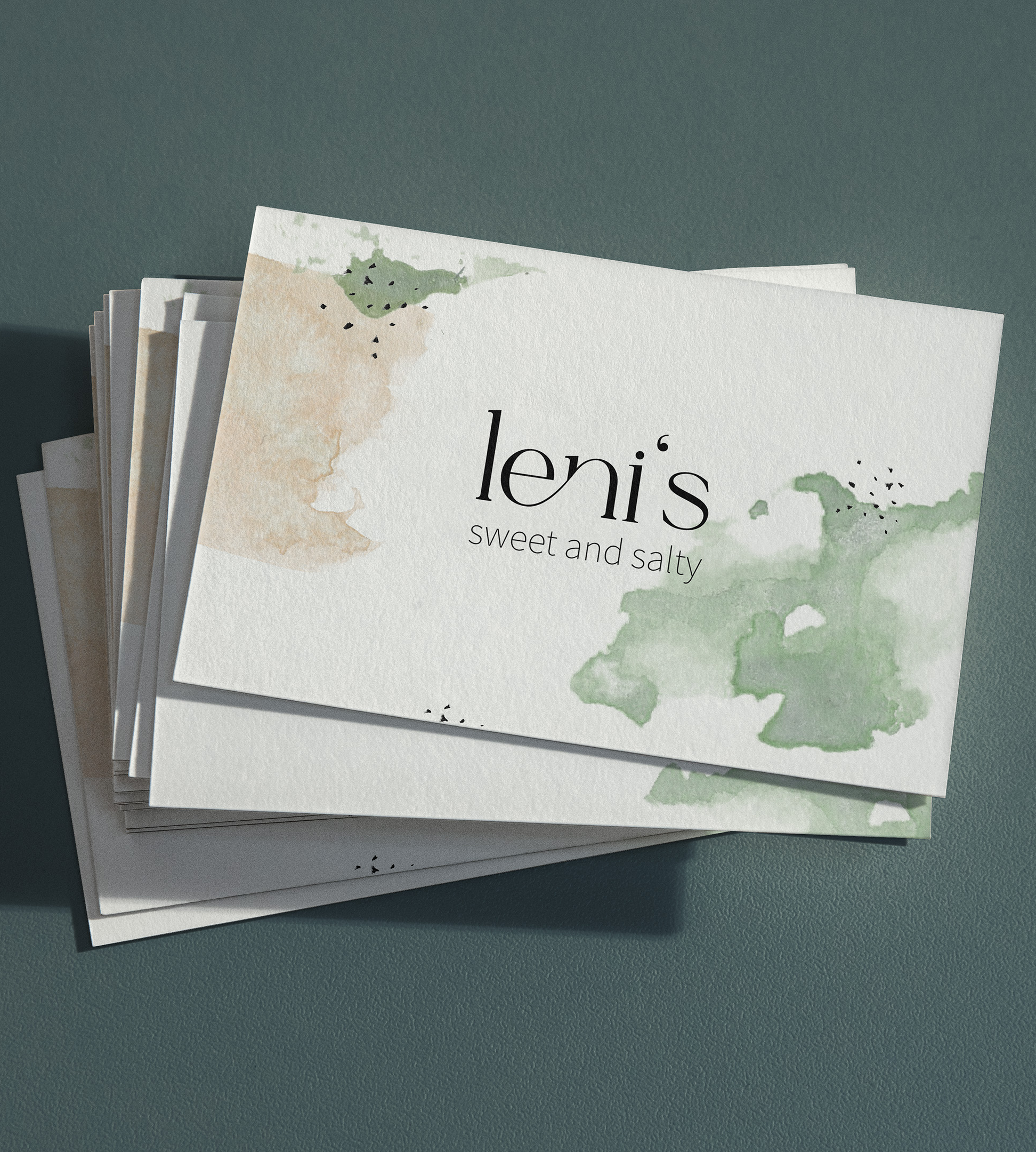 A stack of business cards with the leni's logo. The business cards show the freshness and nature of food through a watercolor design style.