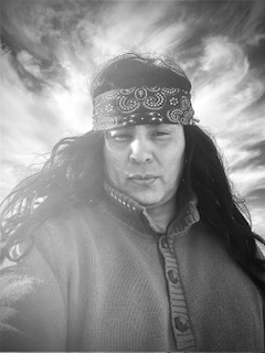 Dramatic black and white portrait — man with bandana against cloudy sky