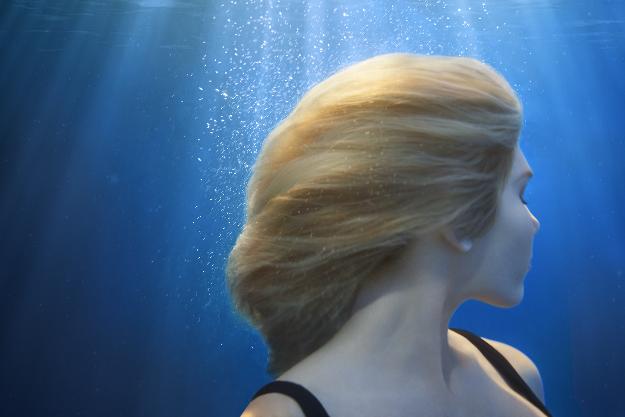 Underwater portrait — woman with hair flowing through blue water