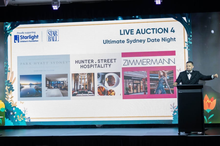 Auctioneer at the lectern presenting a live auction item on the big screen