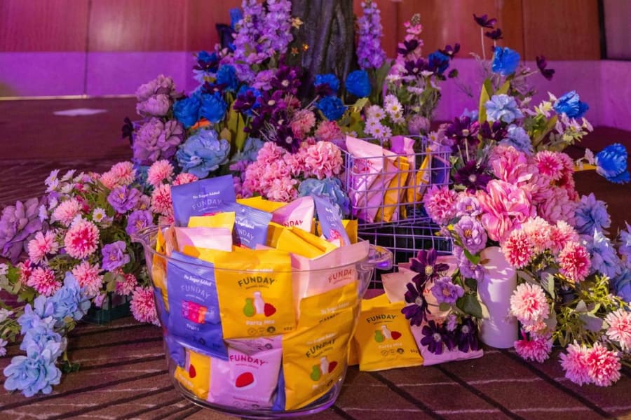 Enchanted lolly tree sponsor activation decorated with flowers and treat bags at a charity gala
