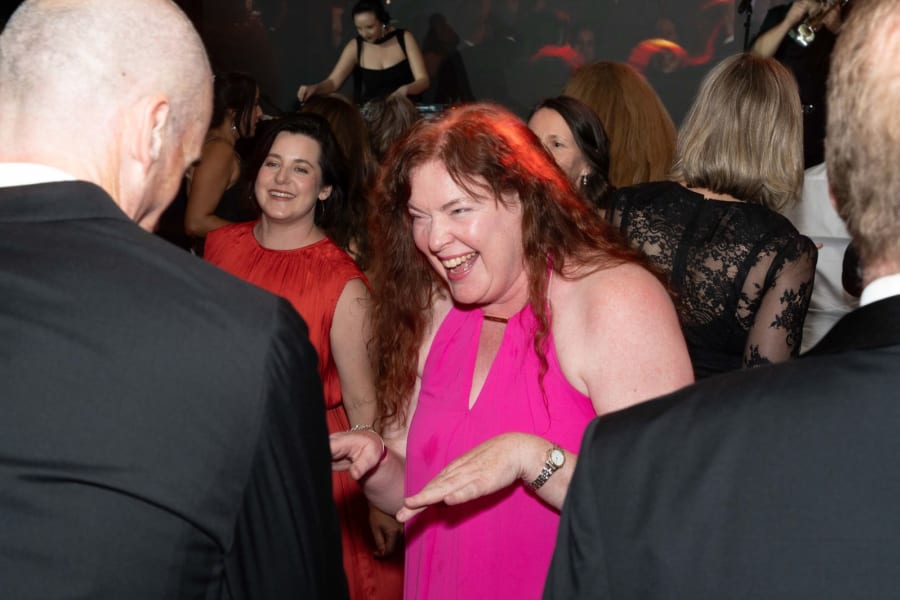 Guest in a pink dress laughing on the dance floor