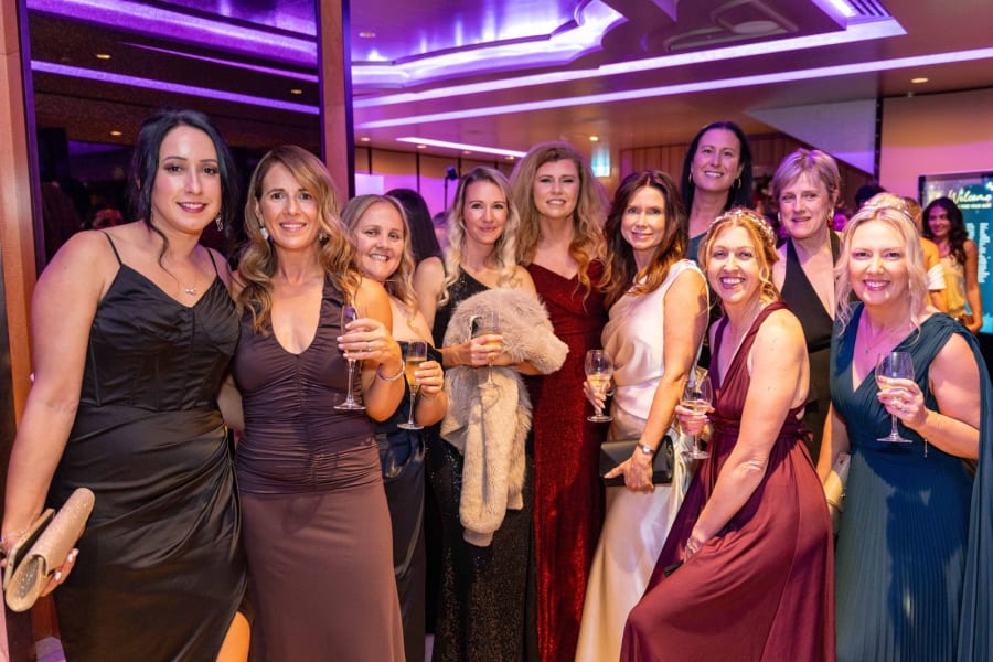Group of gala guests in evening gowns holding champagne on arrival at a Sydney hotel ballroom
