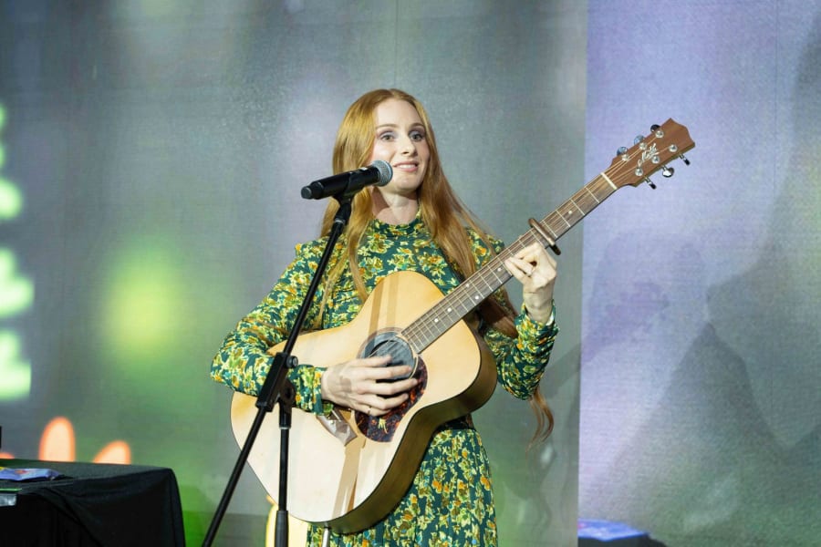 Singer performing with an acoustic guitar on stage at a Sydney charity gala