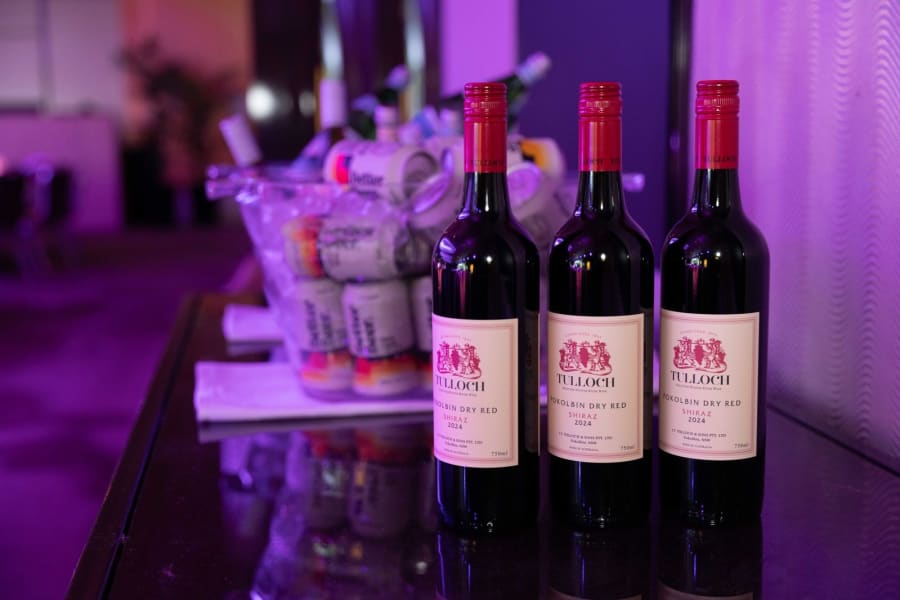 Three bottles of sponsor Shiraz on a bar under purple event lighting