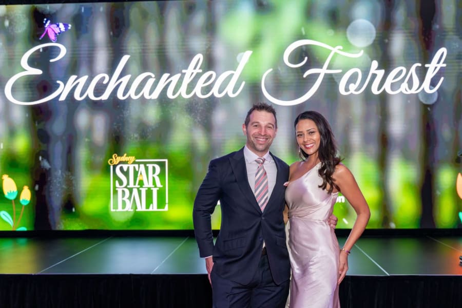 Couple posing in front of the Enchanted Forest stage screen at the Sydney Star Ball