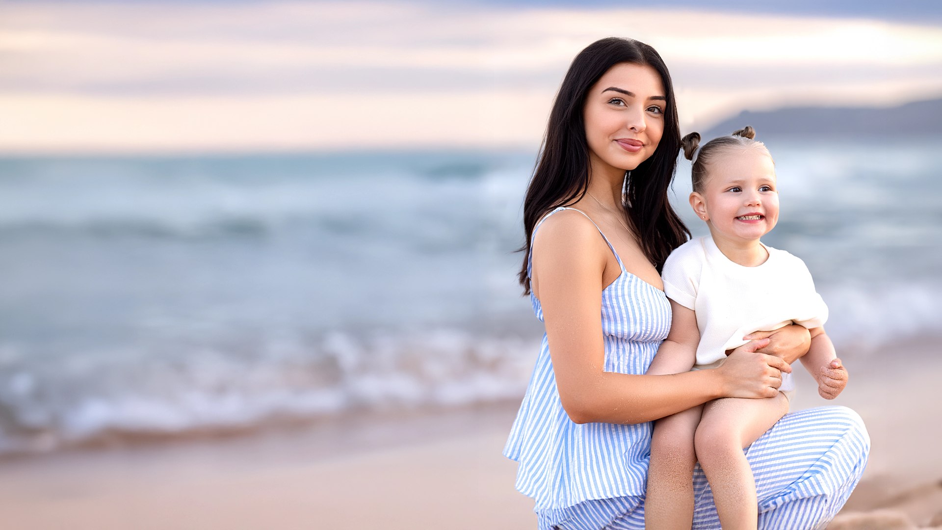 Sydney family photographer capturing a mother and daughter smiling together at the beach at sunset