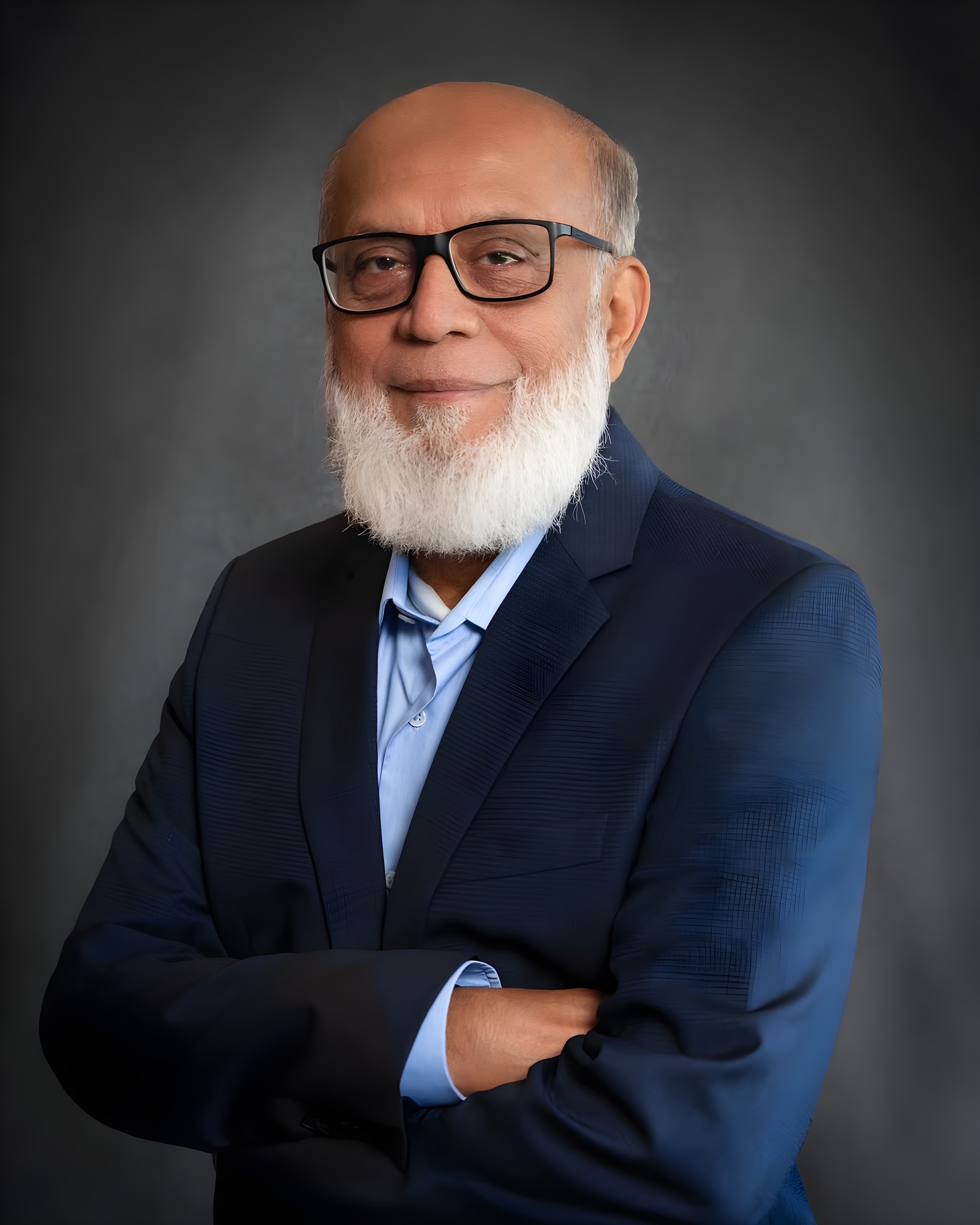 Executive portrait of an older businessman with a white beard, wearing a navy jacket