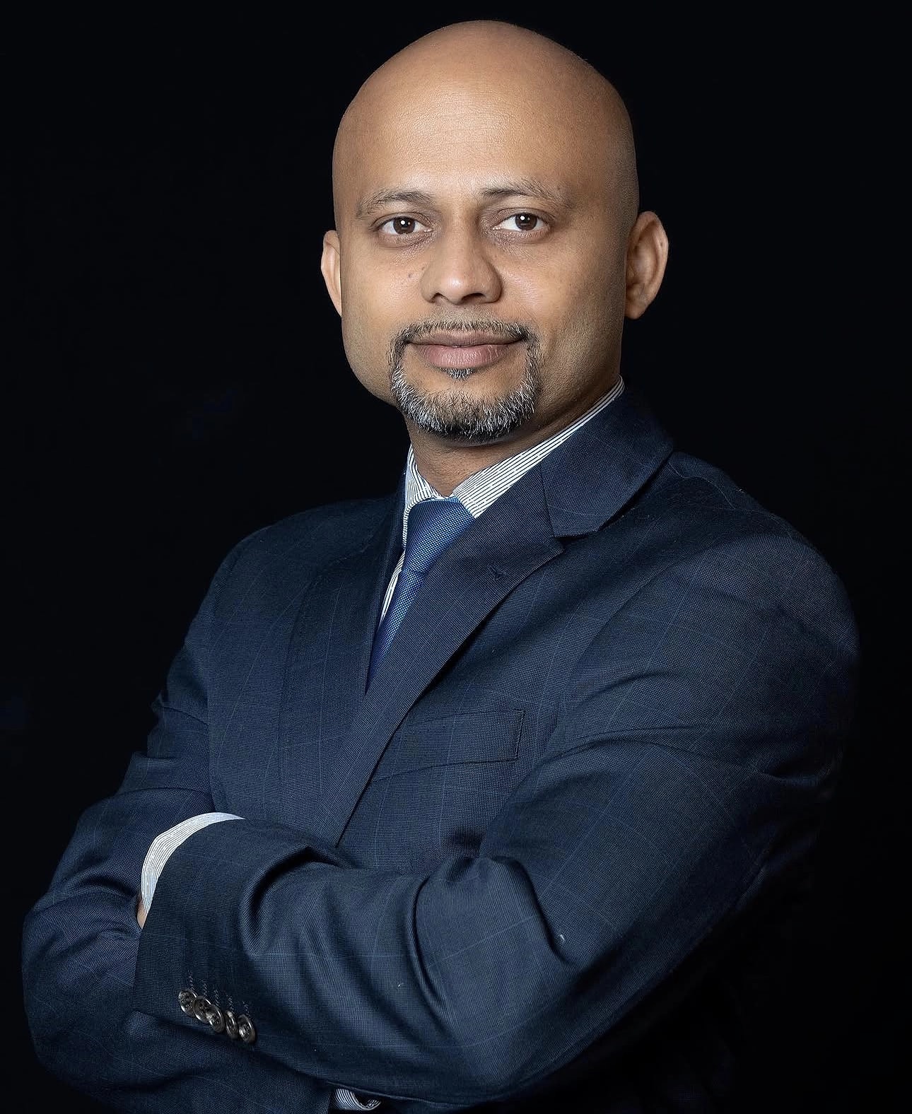 Corporate headshot of a man in a dark suit with arms crossed, photographed in Sydney