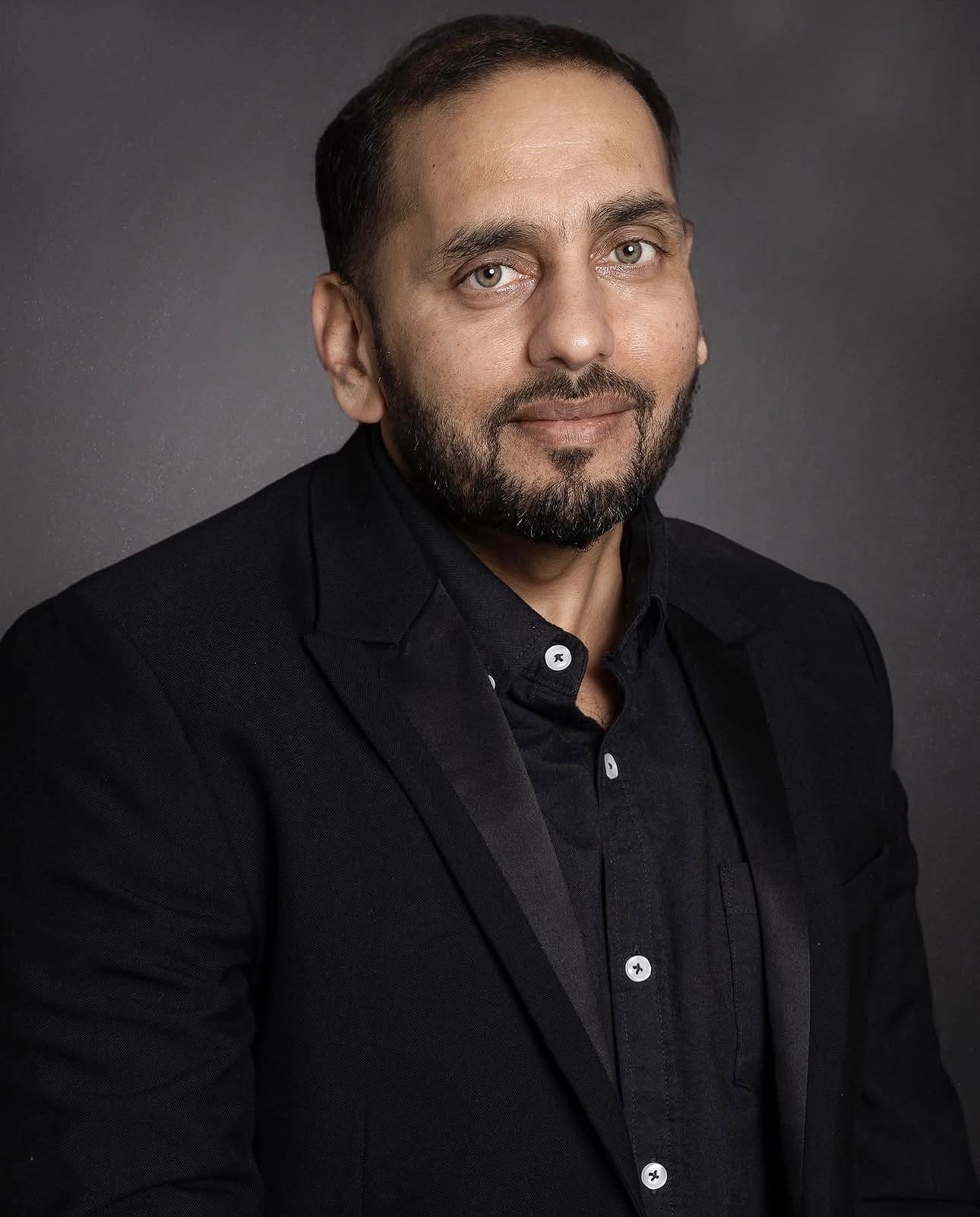 Professional executive portrait of a bearded man in a black suit