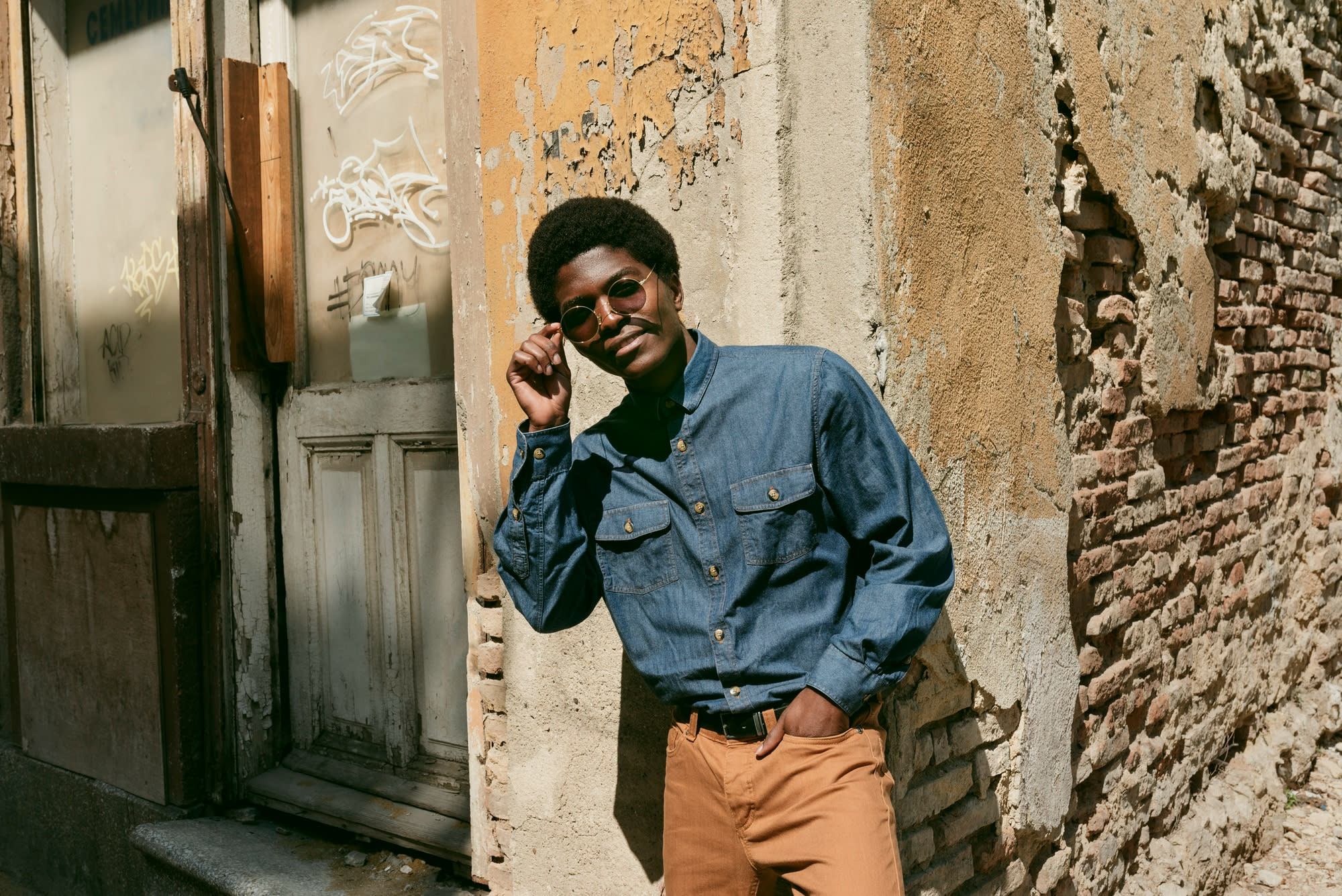 Editorial portrait of a man in denim and tailored trousers, photographed for The Deluxe Place