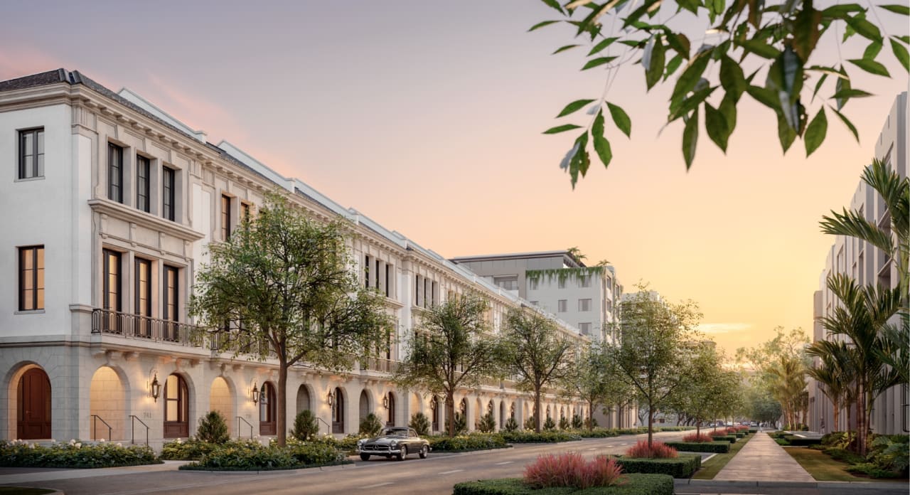 Street-level view of The George townhomes at dusk, limestone columns and iron balconies framed by canopy trees